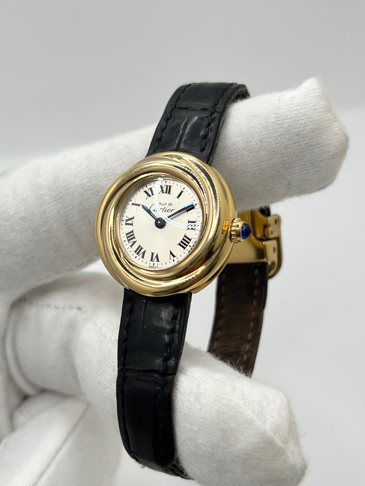 Montre Cartier Trinity référence 2735 pour femme en argent avec boîtier de 27 mm, cadran blanc à chiffres romains et verre saphir. Cette montre Cartier Trinity à mouvement quartz est équipée d’un bracelet en cuir avec boucle déployante en acier. Son design intemporel et élégant en fait une montre de luxe vintage idéale pour les collectionneuses ou pour un usage quotidien. Modèle d’occasion en très bon état, avec de légères traces d’usure, livré avec son coffret d’origine.