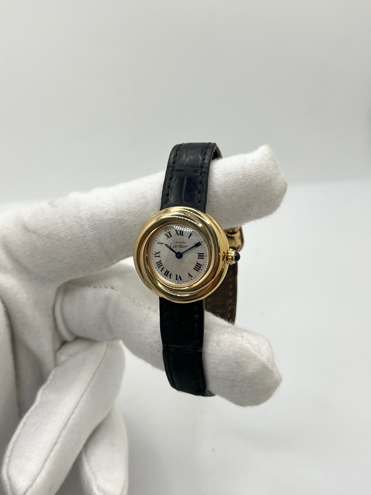 Montre Cartier Trinity référence 2735 pour femme en argent avec boîtier de 27 mm, cadran blanc à chiffres romains et verre saphir. Cette montre Cartier Trinity à mouvement quartz est équipée d’un bracelet en cuir avec boucle déployante en acier. Son design intemporel et élégant en fait une montre de luxe vintage idéale pour les collectionneuses ou pour un usage quotidien. Modèle d’occasion en très bon état, avec de légères traces d’usure, livré avec son coffret d’origine.