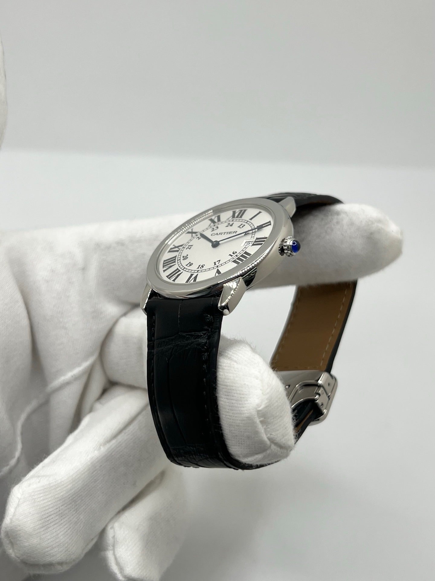 Montre Cartier Ronde Solo en acier avec cadran argent à chiffres romains, mouvement quartz et fonction date. Boîtier rond 36 x 39 mm avec verre saphir et étanchéité 3 ATM. Bracelet en cuir noir avec boucle ardillon en acier. Design classique et élégant, idéal pour homme ou unisexe. Montre d’occasion en très bon état, révisée, avec coffret d’origine.