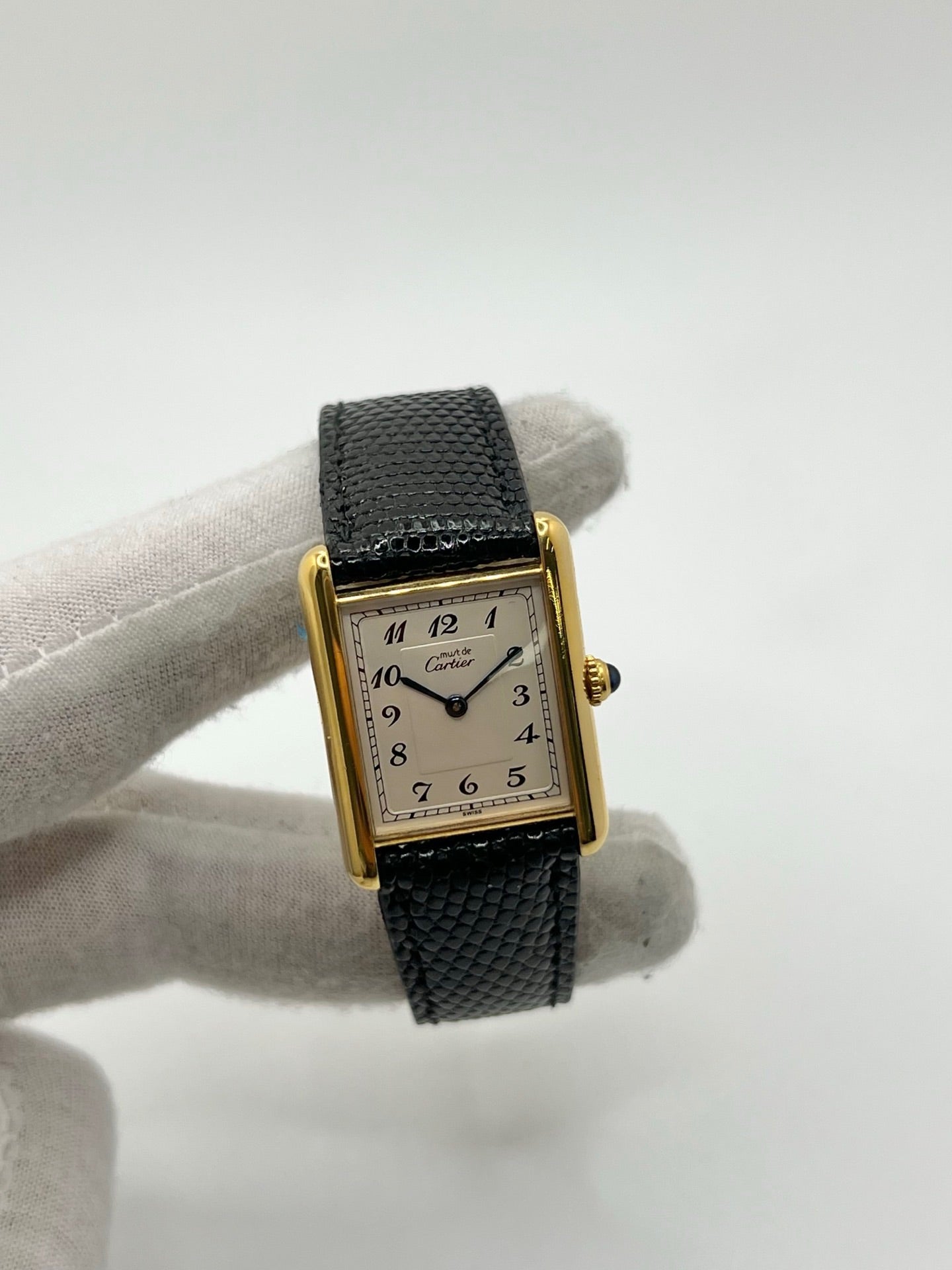 Montre Cartier Tank Vermeil référence 590005 vintage de 1989, avec boîtier rectangulaire en argent aux proportions classiques 23 x 30 mm, cadran argenté élégant avec chiffres arabes noirs et aiguilles bleuies, verre saphir et mouvement quartz. Montée sur un bracelet en cuir de lézard noir avec boucle ardillon en acier. Modèle iconique au design intemporel, livré avec son coffret et ses papiers d’origine, en très bon état.