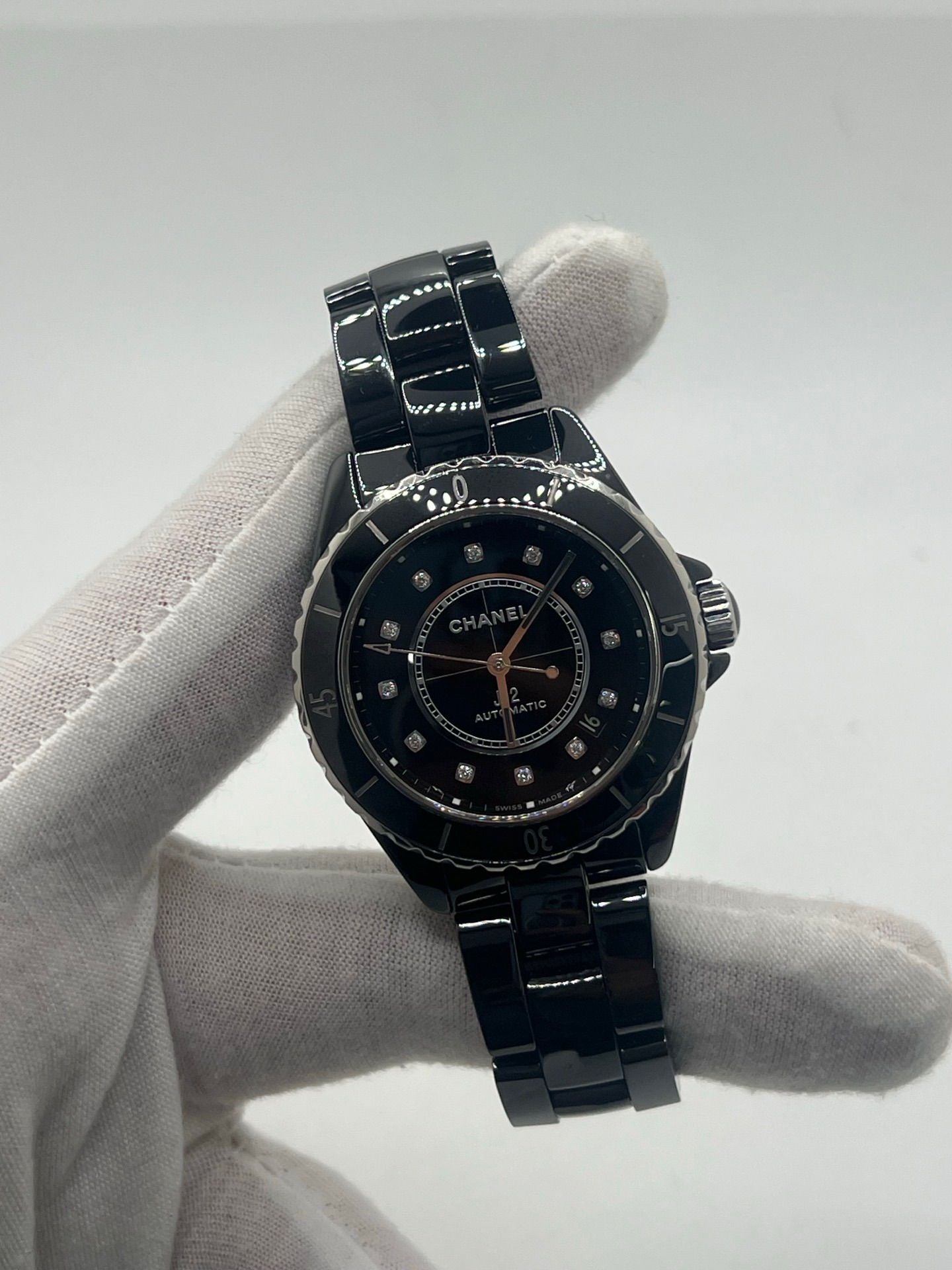 Montre Chanel J12 12.1 en céramique noire avec sertissage de diamants, alliant élégance et performance. Mouvement automatique de précision, boîtier de 38 mm et verre saphir. Modèle de luxe d'occasion en excellent état, livré avec coffret d'origine. Idéal pour collectionneurs et amateurs de haute horlogerie.
