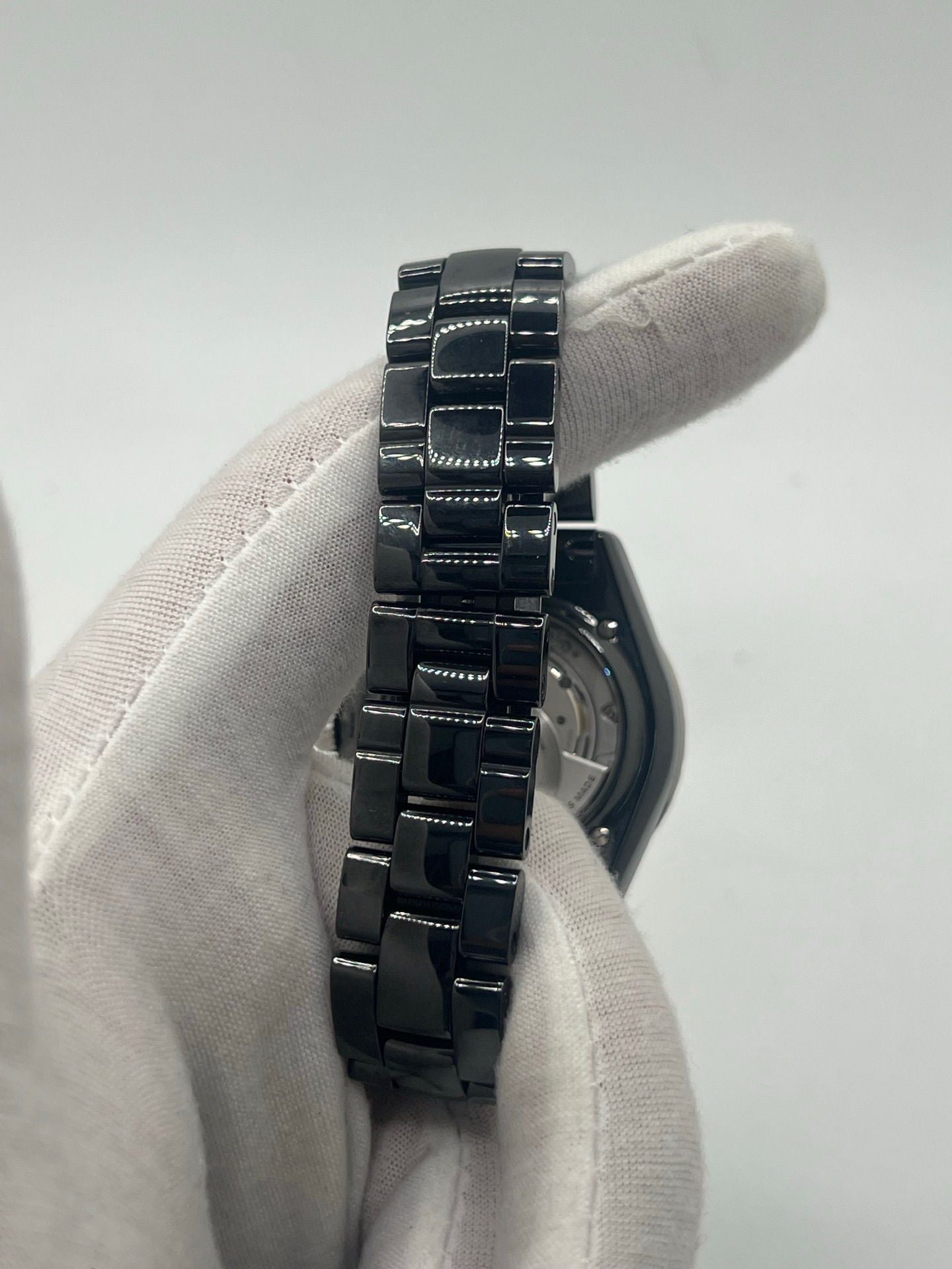 Montre Chanel J12 12.1 en céramique noire avec sertissage de diamants, alliant élégance et performance. Mouvement automatique de précision, boîtier de 38 mm et verre saphir. Modèle de luxe d'occasion en excellent état, livré avec coffret d'origine. Idéal pour collectionneurs et amateurs de haute horlogerie.