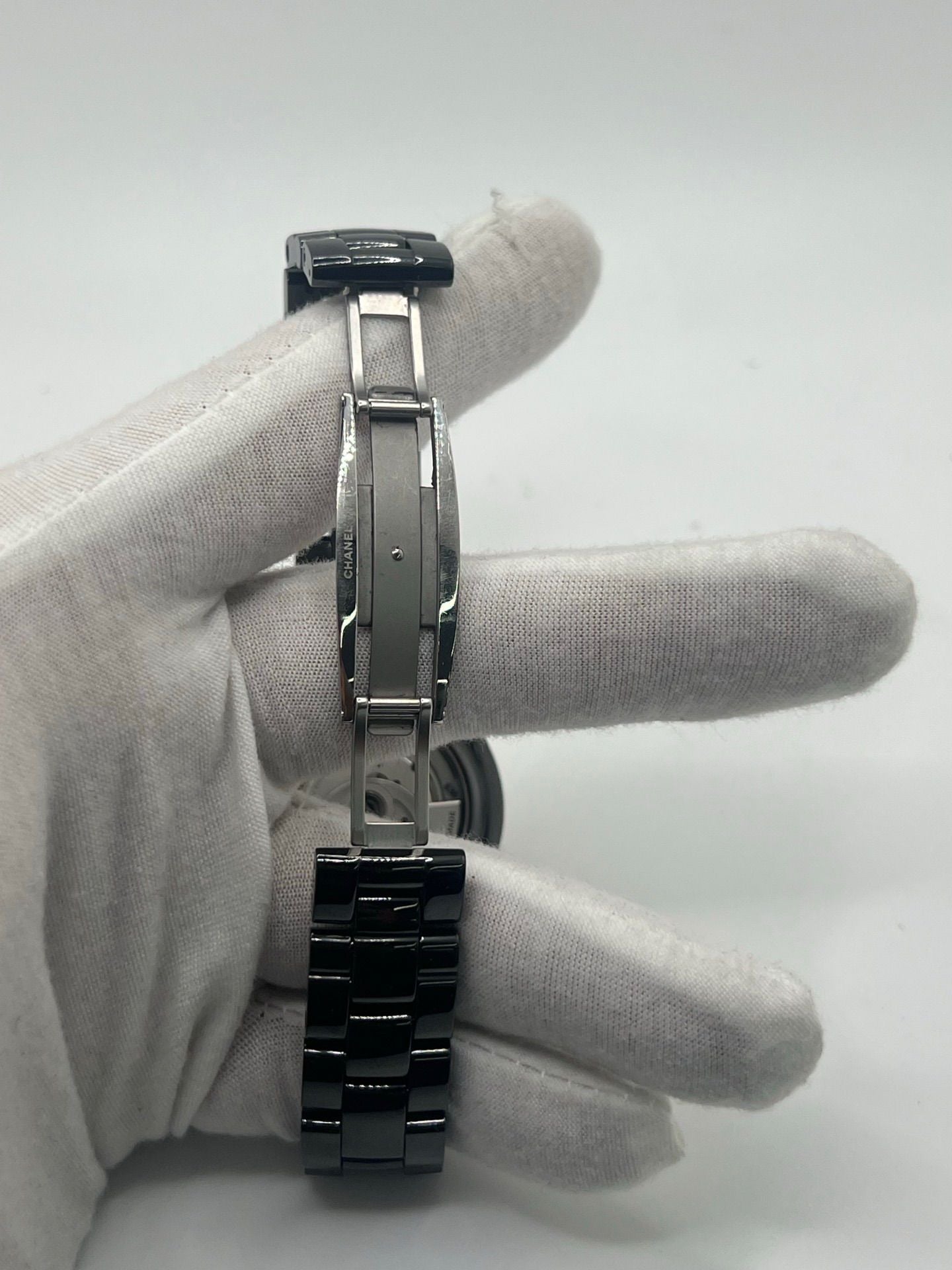 Montre Chanel J12 12.1 en céramique noire avec sertissage de diamants, alliant élégance et performance. Mouvement automatique de précision, boîtier de 38 mm et verre saphir. Modèle de luxe d'occasion en excellent état, livré avec coffret d'origine. Idéal pour collectionneurs et amateurs de haute horlogerie.