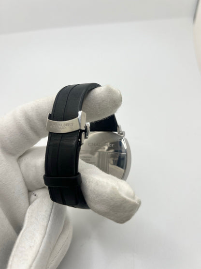 Montre Chaumet Dandy réf. 1229 pour homme ou unisexe, dotée d’un mouvement automatique. Boîtier en acier de 40 mm avec lunette assortie et verre saphir résistant aux rayures. Cadran noir à index bâtons, fonction chronographe et affichage de la date. Bracelet en cuir noir avec boucle déployante en acier. Montre de luxe d’occasion en très bon état, présentant de légères traces d’usure. Révisée en interne le 23 juin 2026, livrée avec coffret d’origine, sans papiers. Disponible à Paris. 
