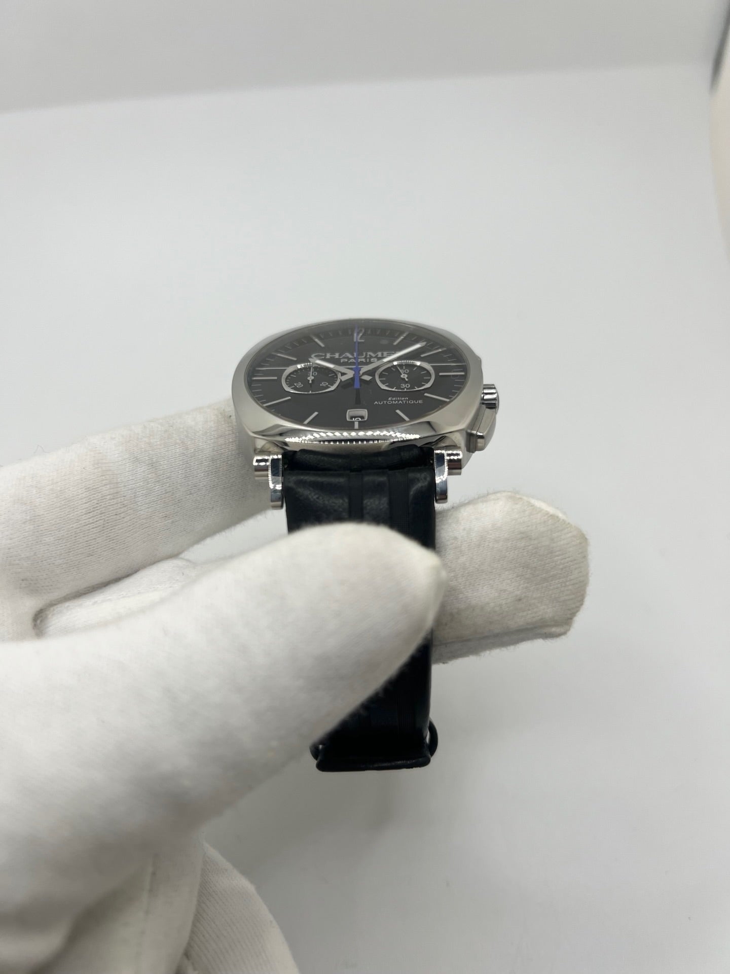 Montre Chaumet Dandy réf. 1229 pour homme ou unisexe, dotée d’un mouvement automatique. Boîtier en acier de 40 mm avec lunette assortie et verre saphir résistant aux rayures. Cadran noir à index bâtons, fonction chronographe et affichage de la date. Bracelet en cuir noir avec boucle déployante en acier. Montre de luxe d’occasion en très bon état, présentant de légères traces d’usure. Révisée en interne le 23 juin 2026, livrée avec coffret d’origine, sans papiers. Disponible à Paris. 