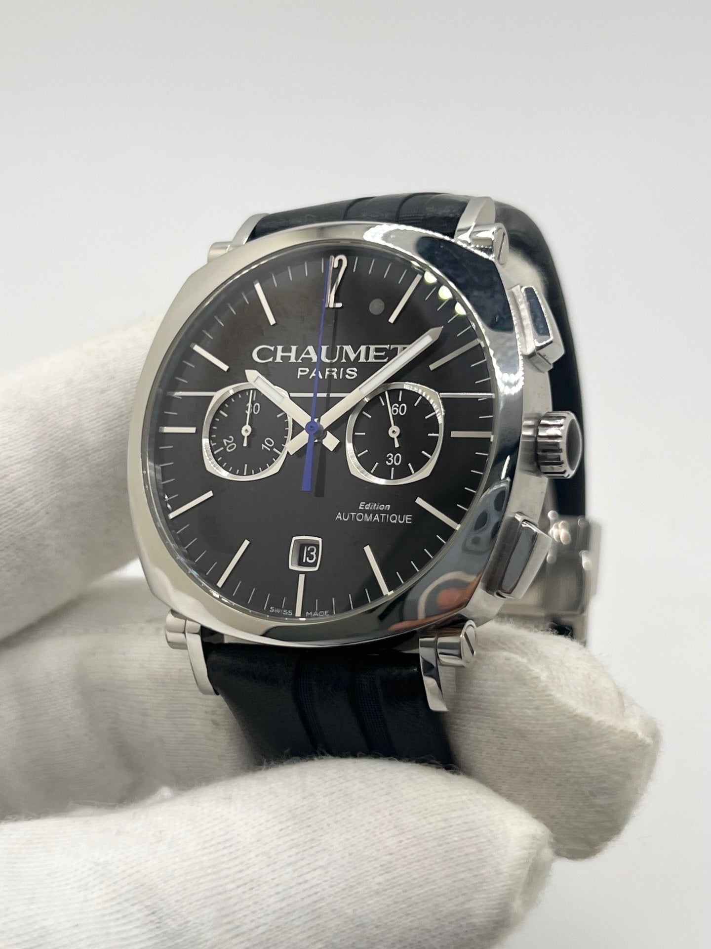 Montre Chaumet Dandy réf. 1229 pour homme ou unisexe, dotée d’un mouvement automatique. Boîtier en acier de 40 mm avec lunette assortie et verre saphir résistant aux rayures. Cadran noir à index bâtons, fonction chronographe et affichage de la date. Bracelet en cuir noir avec boucle déployante en acier. Montre de luxe d’occasion en très bon état, présentant de légères traces d’usure. Révisée en interne le 23 juin 2026, livrée avec coffret d’origine, sans papiers. Disponible à Paris. 