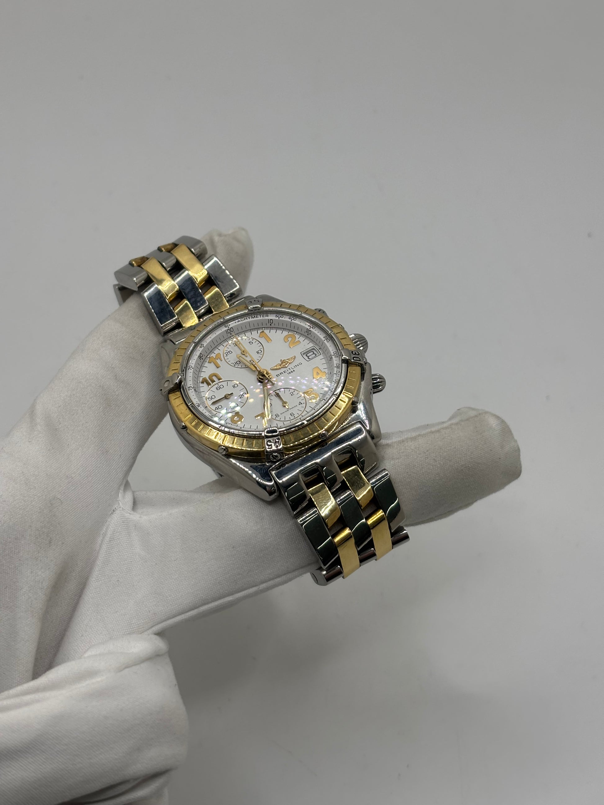 Montre Breitling Chronomat B13050.1 en or et acier avec boîtier de 39 mm, cadran blanc à chiffres arabes, verre saphir et mouvement automatique Breitling 13 basé sur l'ETA Valjoux 7750. Ce chronographe est équipé d'un bracelet en or et acier avec boucle déployante d'origine. Révisée, en excellent état et garantie 1 an, cette montre de luxe suisse allie élégance intemporelle, précision horlogère et finitions haut de gamme.