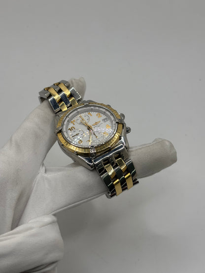 Montre Breitling Chronomat B13050.1 en or et acier avec boîtier de 39 mm, cadran blanc à chiffres arabes, verre saphir et mouvement automatique Breitling 13 basé sur l'ETA Valjoux 7750. Ce chronographe est équipé d'un bracelet en or et acier avec boucle déployante d'origine. Révisée, en excellent état et garantie 1 an, cette montre de luxe suisse allie élégance intemporelle, précision horlogère et finitions haut de gamme.