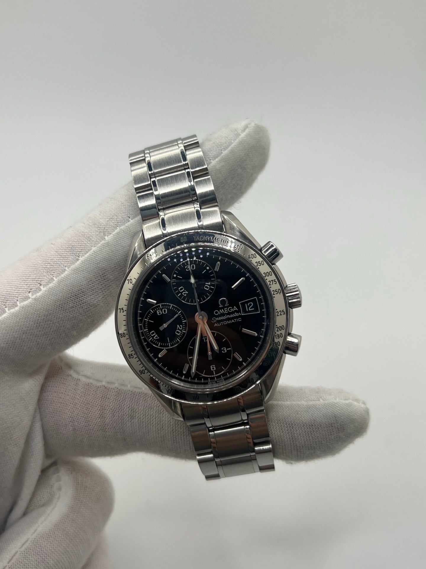 Montre Omega Speedmaster Date référence 3513.50 en acier, chronographe automatique avec boîtier de 39 mm et bracelet en acier assorti. Cadran noir sobre sans chiffres, protégé par un verre saphir, avec affichage de la date et fonctions chronographe. Modèle étanche 5 ATM, animé par le calibre automatique 1152 offrant 44 heures de réserve de marche. Montre homme élégante et sportive, emblématique de la collection Speedmaster.