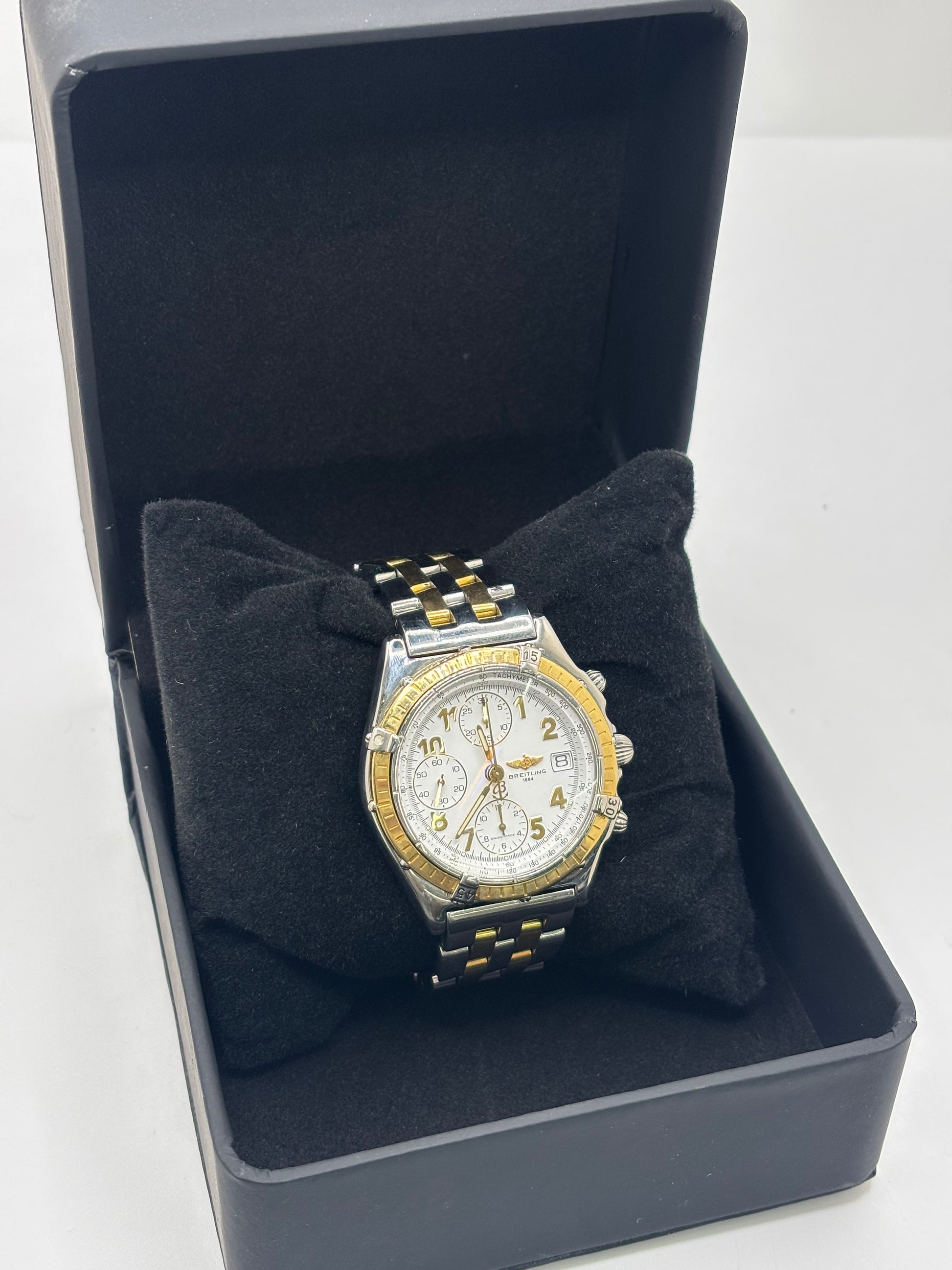 Montre Breitling Chronomat B13050.1 en or et acier avec boîtier de 39 mm, cadran blanc à chiffres arabes, verre saphir et mouvement automatique Breitling 13 basé sur l'ETA Valjoux 7750. Ce chronographe est équipé d'un bracelet en or et acier avec boucle déployante d'origine. Révisée, en excellent état et garantie 1 an, cette montre de luxe suisse allie élégance intemporelle, précision horlogère et finitions haut de gamme.