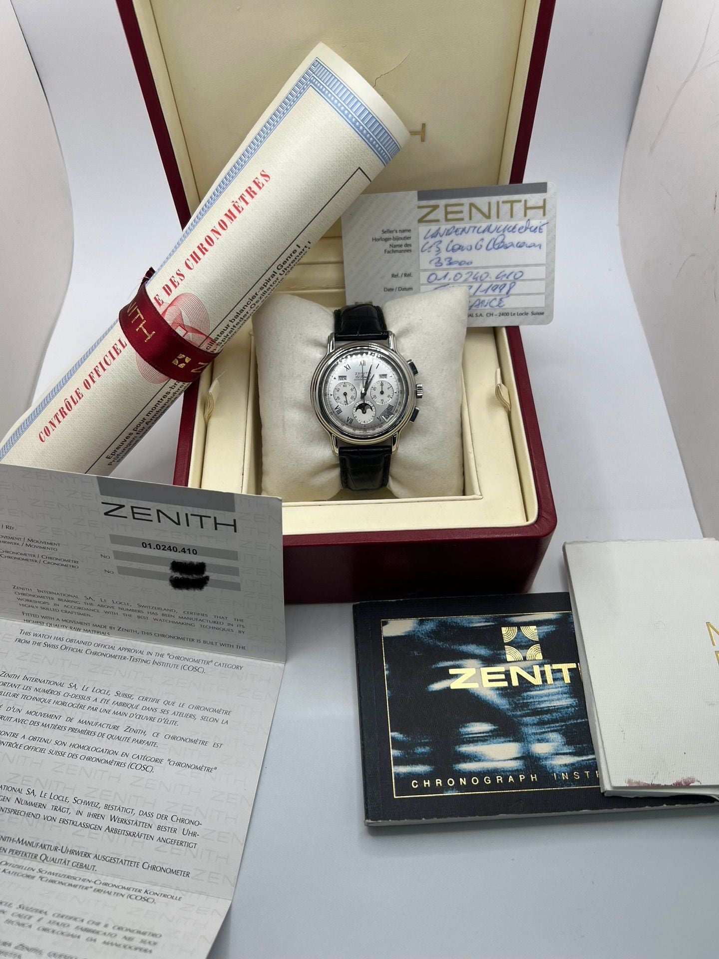 Montre chronographe automatique en acier avec cadran argenté à chiffres romains, fonction phase lunaire, date, jour et mois. Boîtier de 40 mm, verre saphir, fond transparent et bracelet en cuir noir. Modèle de haute précision doté du calibre 410 avec 50 heures de réserve de marche. Montre élégante pour homme ou unisexe.