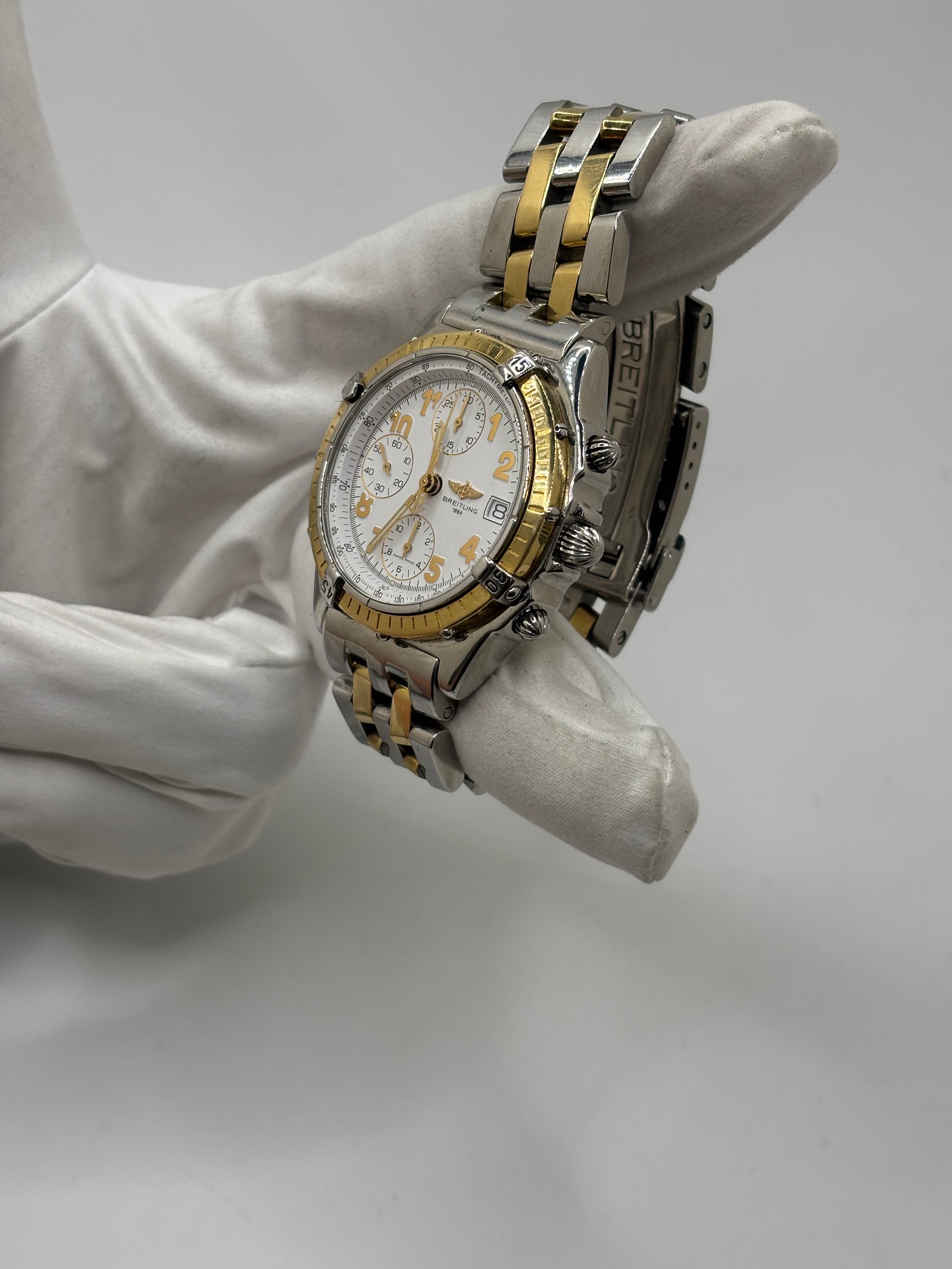 Montre Breitling Chronomat B13050.1 en or et acier avec boîtier de 39 mm, cadran blanc à chiffres arabes, verre saphir et mouvement automatique Breitling 13 basé sur l'ETA Valjoux 7750. Ce chronographe est équipé d'un bracelet en or et acier avec boucle déployante d'origine. Révisée, en excellent état et garantie 1 an, cette montre de luxe suisse allie élégance intemporelle, précision horlogère et finitions haut de gamme.