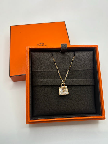 Collier Hermès Sac Birkin en or rose 18K serti de diamants totalisant 0,22 carat. Cette création joaillière raffinée s’inspire de l’iconique sac Birkin et associe l’éclat chaleureux de l’or rose 750 millièmes à la brillance délicate des diamants. Bijou de luxe élégant et féminin, idéal pour une collection de haute joaillerie, une occasion spéciale ou un cadeau précieux. Finitions soignées et design emblématique signé Hermès.
