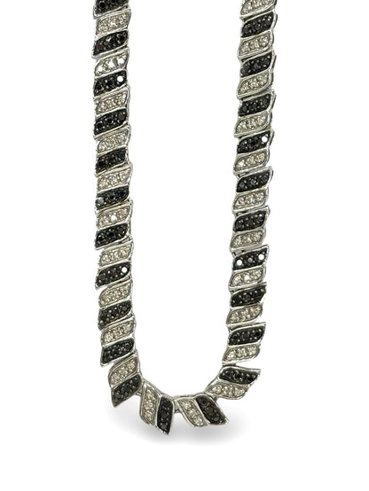 Élégant collier en or blanc 18 carats sublimé par des diamants noirs et incolores totalisant 2 carats. Un bijou raffiné qui joue sur le contraste entre lumière et obscurité, symbole de sophistication et d’élégance intemporelle, idéal pour sublimer toutes les tenues avec éclat et modernité.