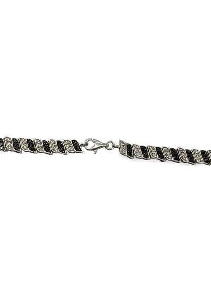 Élégant collier en or blanc 18 carats sublimé par des diamants noirs et incolores totalisant 2 carats. Un bijou raffiné qui joue sur le contraste entre lumière et obscurité, symbole de sophistication et d’élégance intemporelle, idéal pour sublimer toutes les tenues avec éclat et modernité.