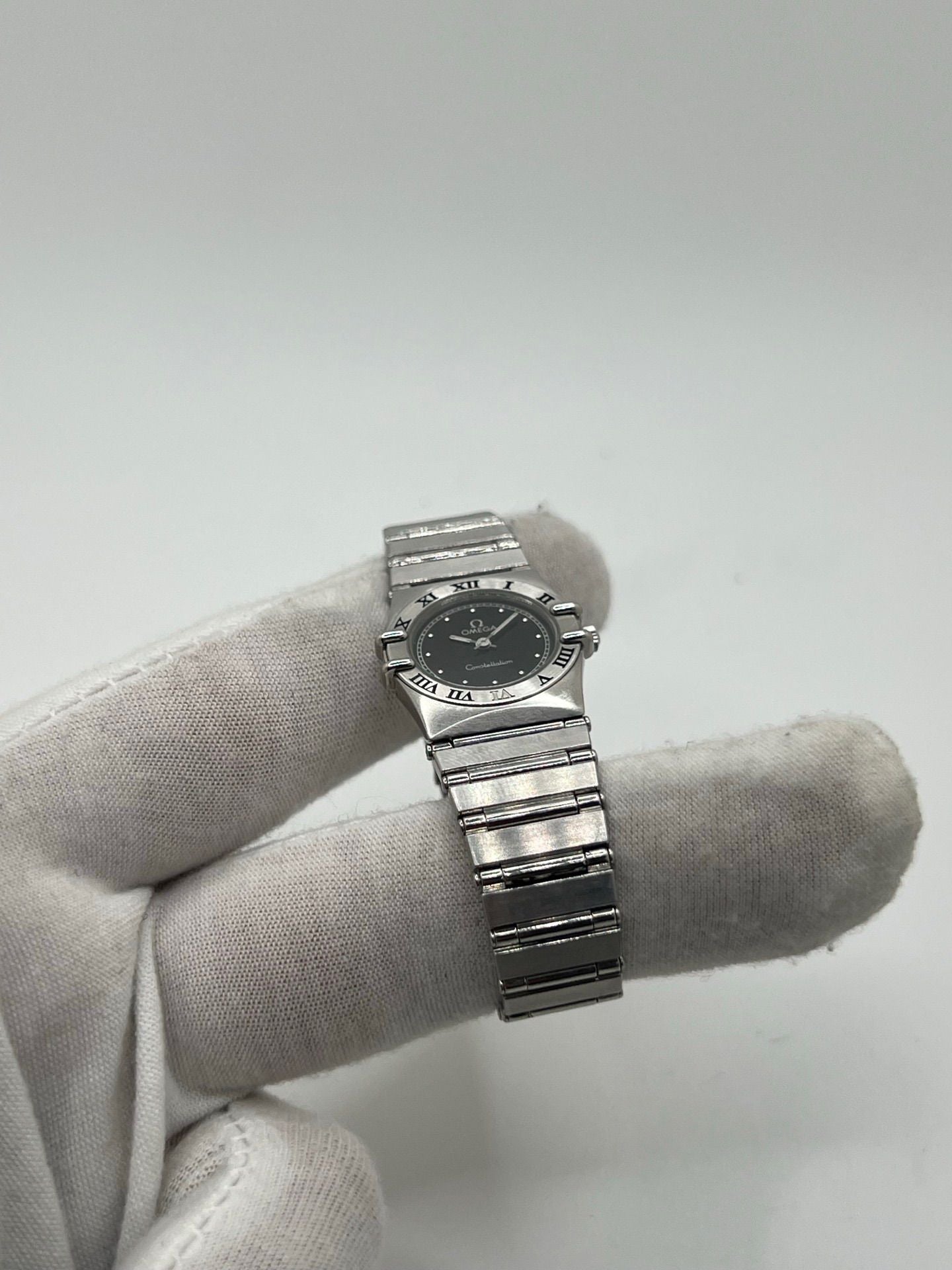 Montre femme Omega Constellation 795.1080 en acier avec cadran noir et chiffres romains. Mouvement quartz fiable, bracelet bicolore Or/Acier avec boucle pli. Diamètre 22 mm, verre saphir. État très bon, légère usure discrète. Coffret d’origine inclus, sans papiers. Parfaite pour élégance quotidienne et collection horlogère.