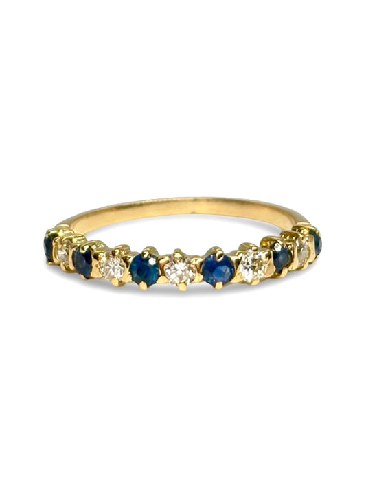 Demi-alliance en or jaune 18 carats sertie de saphirs et diamants totalisant 0,40 carat. Élégante et raffinée, cette bague demi-tour associe l’éclat profond des saphirs à la brillance des diamants pour un rendu lumineux. Idéale comme alliance, bague d’anniversaire ou bijou du quotidien, elle apporte une touche précieuse et intemporelle à chaque tenue.