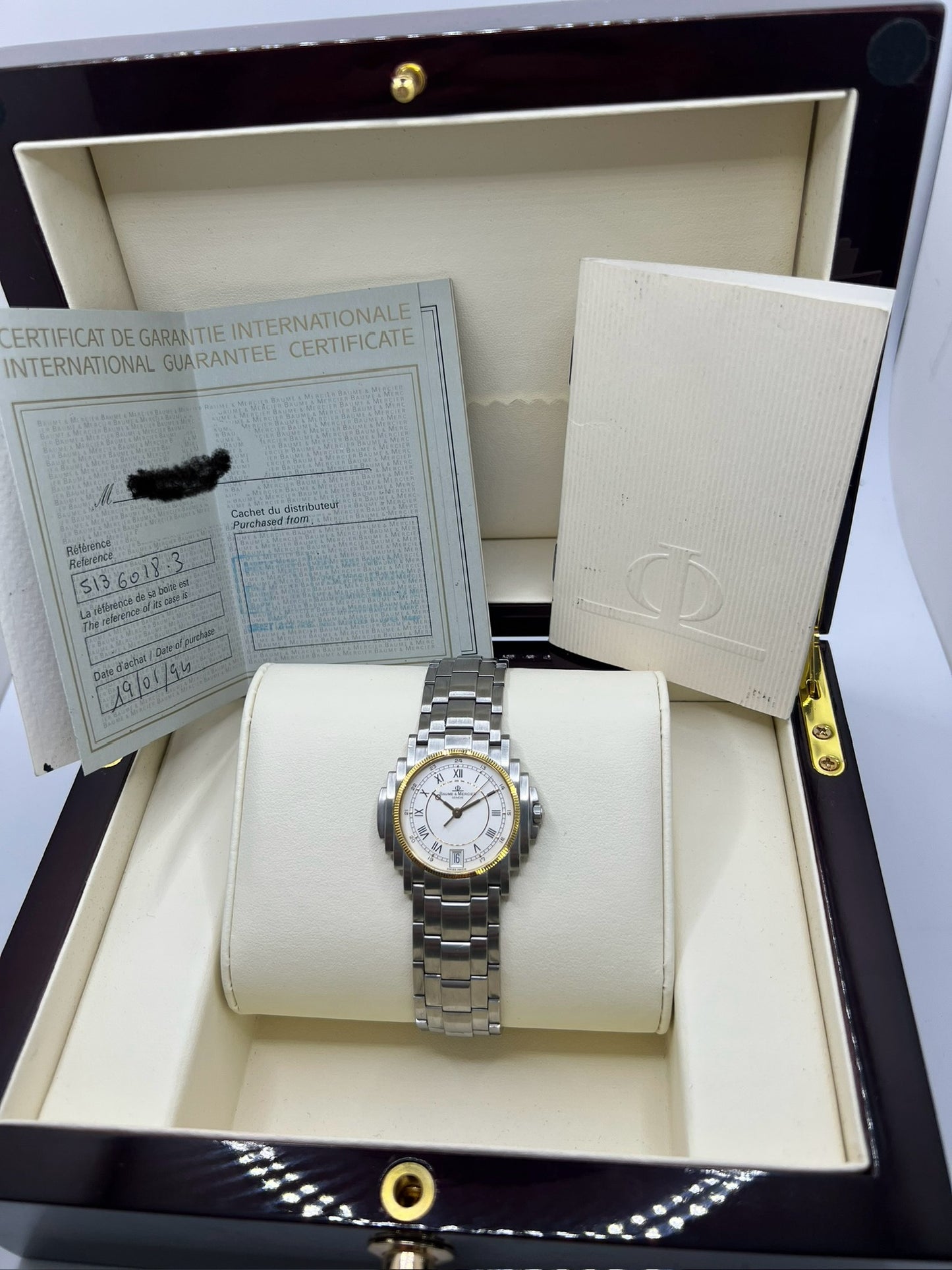 Montre Baume & Mercier 5136.018.3 pour homme/unisexe, boîtier 34 mm en or et acier, cadran blanc à chiffres romains, mouvement quartz précis. Verre saphir résistant aux rayures, bracelet en acier avec boucle double plis. Fonction date. Montre d’occasion en très bon état avec papiers d’origine, élégante et intemporelle.