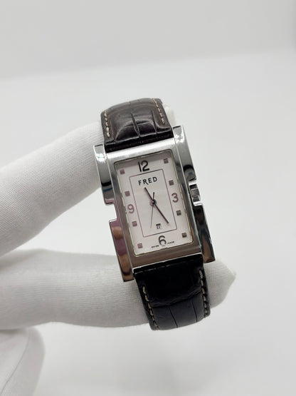 Montre Fred Tank R09-100 en excellent état, dotée d’un mouvement quartz et d’un boîtier en acier de 33 × 27 mm. Cette montre élégante présente un cadran blanc avec chiffres arabes, protégé par un verre saphir. Elle est accompagnée d’un bracelet en cuir brun avec boucle en acier. Modèle homme ou unisexe, cette Fred Tank R09-100 séduit par son design classique et intemporel, idéal pour compléter une tenue élégante au quotidien.
