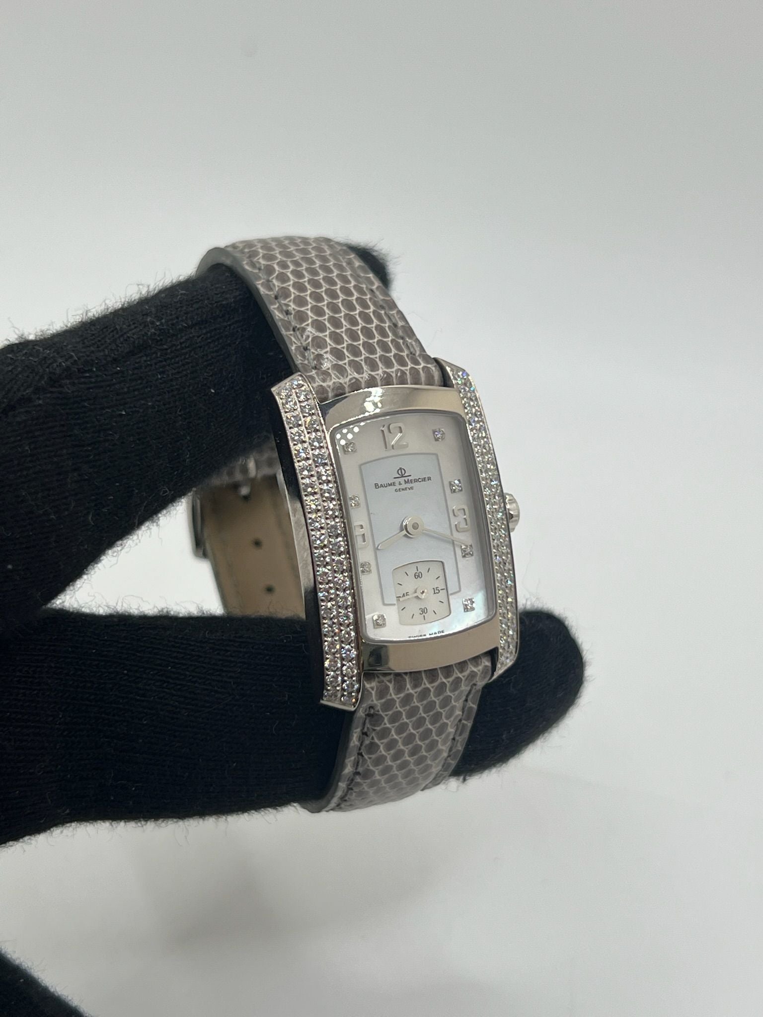 Cette Baume & Mercier Hampton Milleis incarne l’élégance intemporelle avec son boîtier rectangulaire en or blanc 18K, sublimé de diamants. Son cadran aux lignes Art déco reflète l’excellence horlogère suisse. Montée sur un bracelet en cuir de lézard (non d’origine), elle est livrée avec son coffret d’origine. Entièrement révisée en juin 2025 et garantie un an, cette pièce rare allie luxe, raffinement et fiabilité, parfaite pour les passionnés de belles montres.
