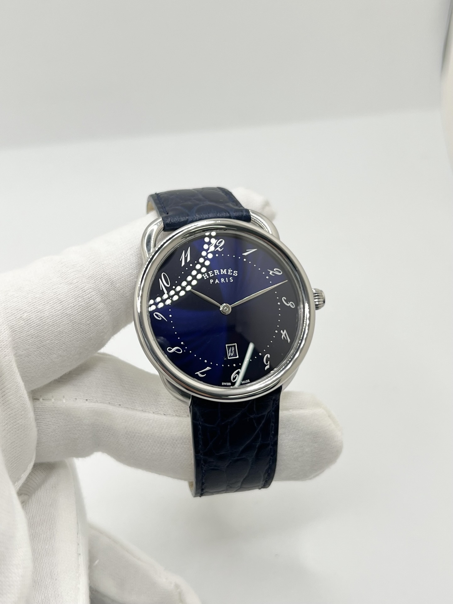 Montre Hermès Arceau grand modèle AR7Q.810 en acier avec cadran blanc épuré, chiffres arabes inclinés signature de la collection Arceau, mouvement quartz précis et bracelet en cuir élégant. Design intemporel et raffiné, idéal pour une tenue chic au quotidien ou une occasion spéciale, alliant savoir-faire horloger et esthétique minimaliste.