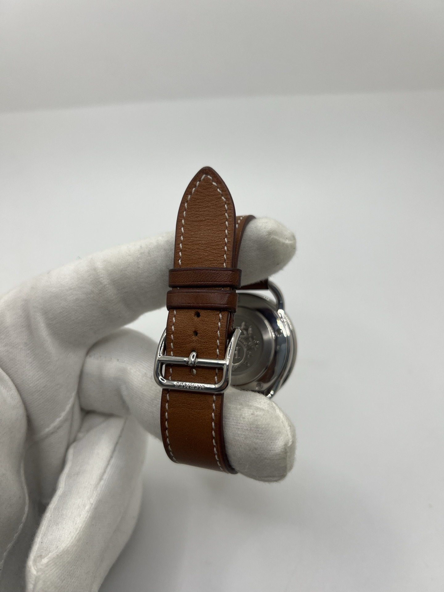 Montre Hermès Arceau Grand Modèle AR5.710 de 2014 en acier 38 mm avec mouvement quartz, cadran blanc à chiffres arabes et bracelet cuir brun d’origine. Cette montre de luxe Hermès Full Set avec boîte et papiers possède un verre saphir, une boucle ardillon acier et le design emblématique Arceau inspiré de l’univers équestre. Montre vintage Hermès élégante, révisée en 2026 et garantie 1 an.