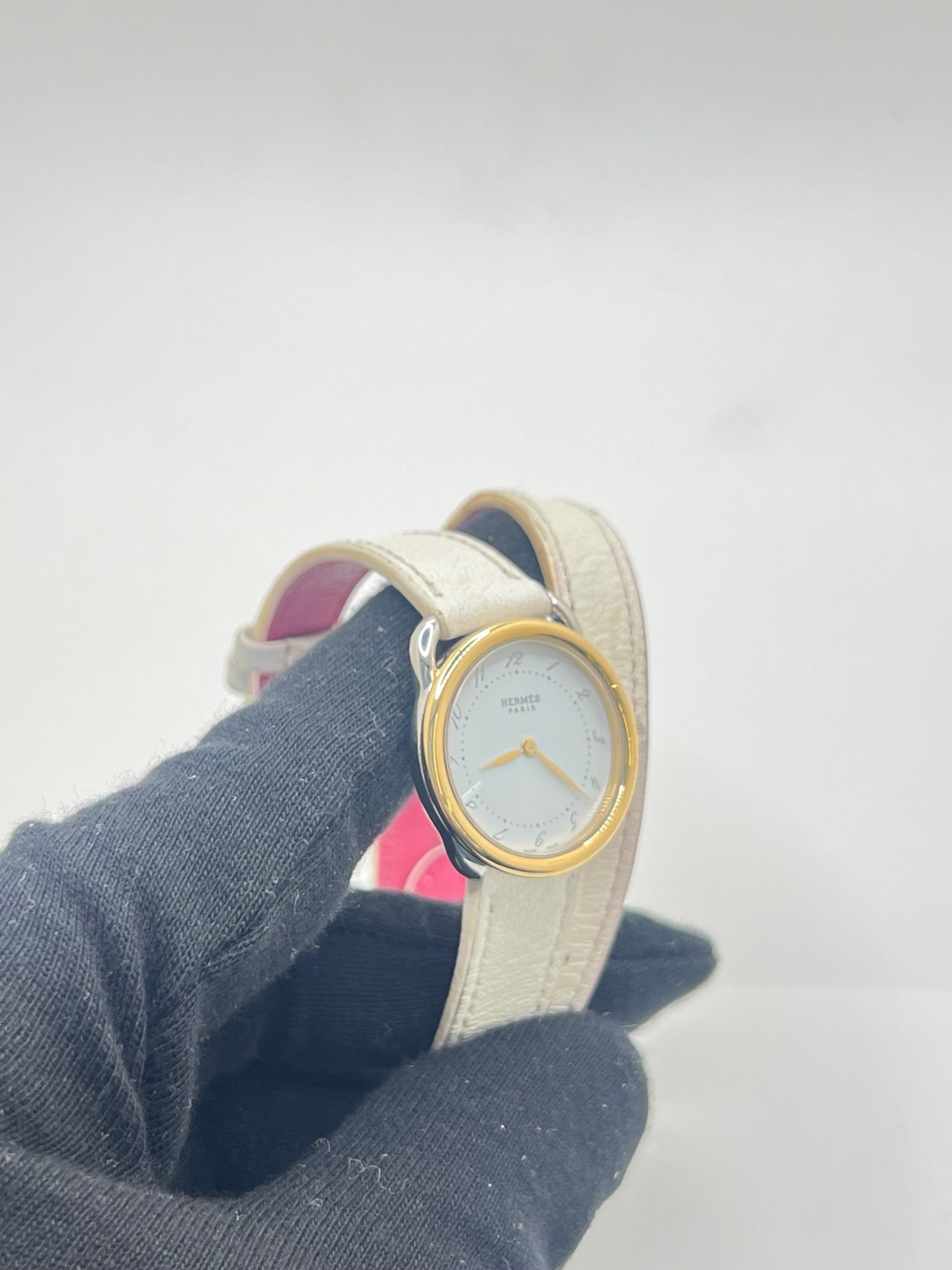 Élégante montre Hermès Arceau pour femme, boîtier en or et acier, cadran blanc aux chiffres arabes et bracelet en cuir beige. Ce garde-temps emblématique allie raffinement et savoir-faire horloger français, offrant un design intemporel et une précision quartz idéale pour un style classique et chic.
