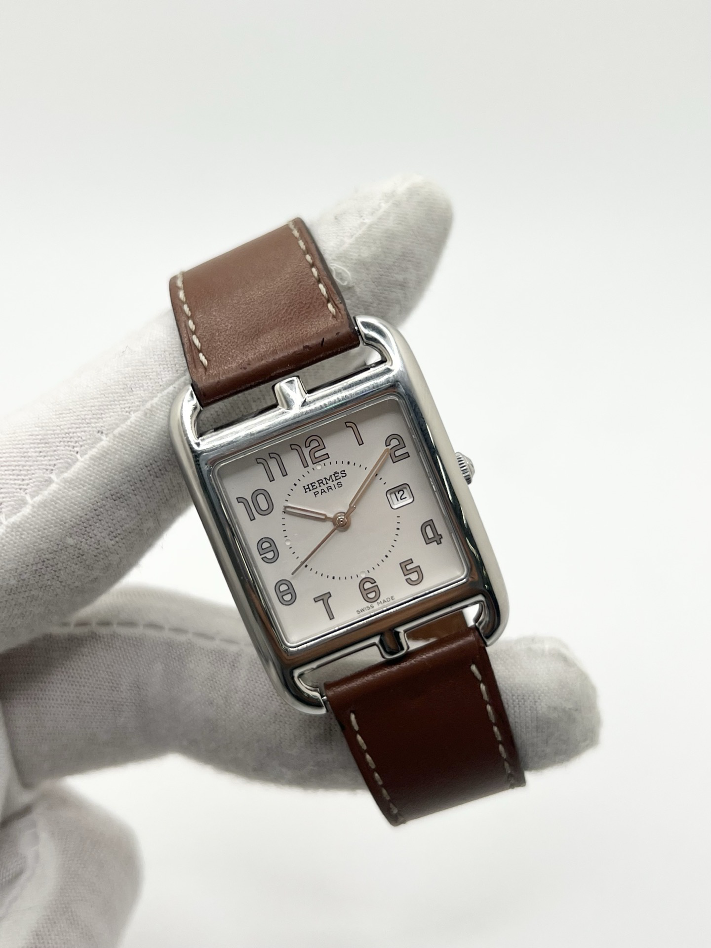 Montre Hermès Cape Cod Grand Modèle en acier inoxydable, boîtier rectangulaire iconique aux lignes élégantes et contemporaines, cadran argenté épuré avec chiffres arabes stylisés et aiguilles fines. Bracelet en cuir signature Hermès offrant confort et raffinement. Mouvement quartz précis. Montre de luxe intemporelle et sophistiquée, idéale pour un porté quotidien ou une tenue habillée, symbole du savoir-faire horloger et du style parisien.