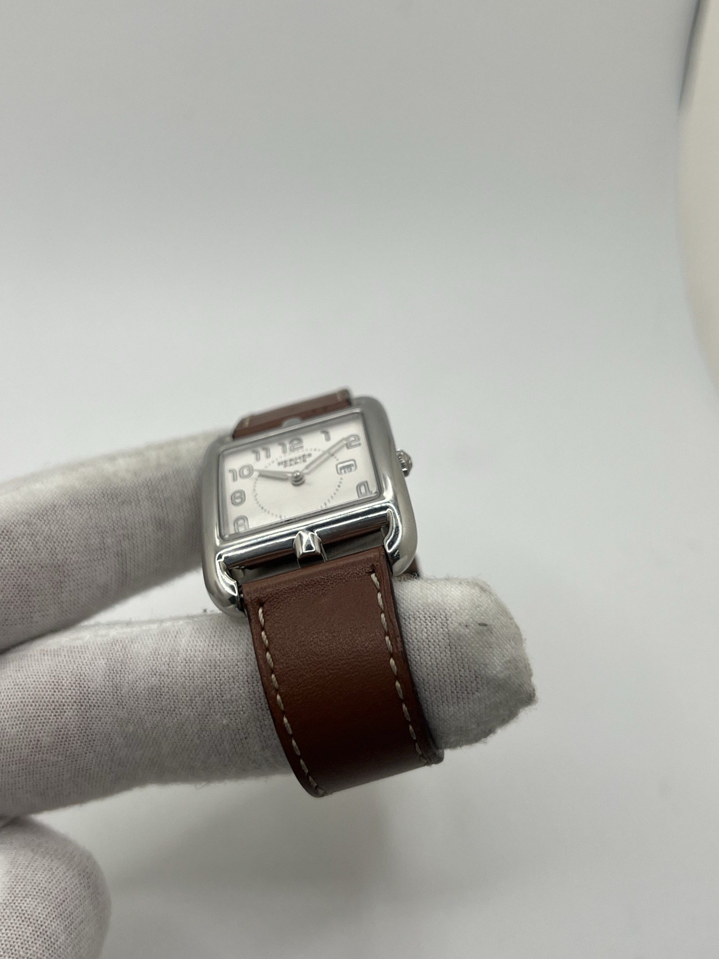 Montre Hermès Cape Cod Grand Modèle en acier inoxydable, boîtier rectangulaire iconique aux lignes élégantes et contemporaines, cadran argenté épuré avec chiffres arabes stylisés et aiguilles fines. Bracelet en cuir signature Hermès offrant confort et raffinement. Mouvement quartz précis. Montre de luxe intemporelle et sophistiquée, idéale pour un porté quotidien ou une tenue habillée, symbole du savoir-faire horloger et du style parisien.