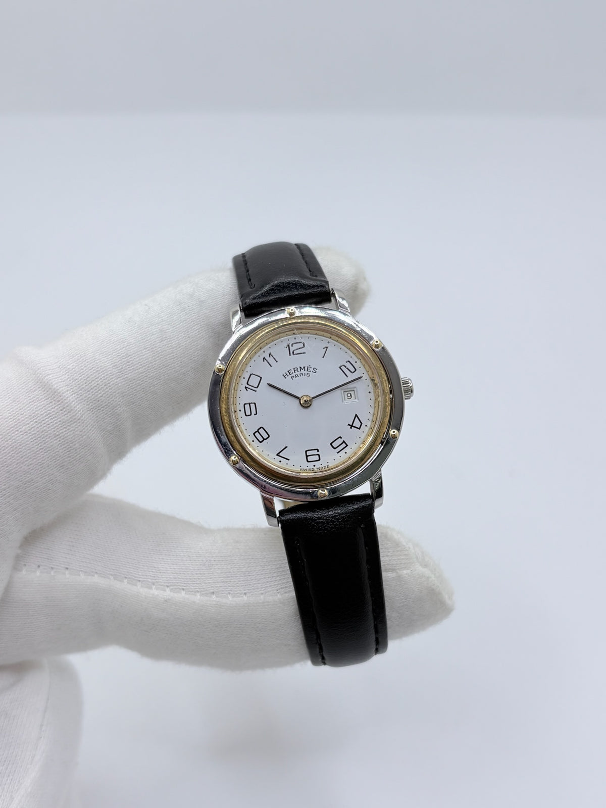 Montre Hermès Clipper pour femme en acier, équipée d’un mouvement à quartz. Son boîtier de 30 mm est associé à une lunette en or jaune, un cadran blanc avec chiffres arabes et un verre saphir. Cette montre Hermès Clipper est montée sur un bracelet en cuir de vache noir avec boucle ardillon en acier. Un modèle élégant et intemporel de la collection Clipper, idéal pour les amateurs de montres de luxe.