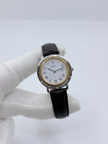 Montre Hermès Clipper pour femme en acier, équipée d’un mouvement à quartz. Son boîtier de 30 mm est associé à une lunette en or jaune, un cadran blanc avec chiffres arabes et un verre saphir. Cette montre Hermès Clipper est montée sur un bracelet en cuir de vache noir avec boucle ardillon en acier. Un modèle élégant et intemporel de la collection Clipper, idéal pour les amateurs de montres de luxe.