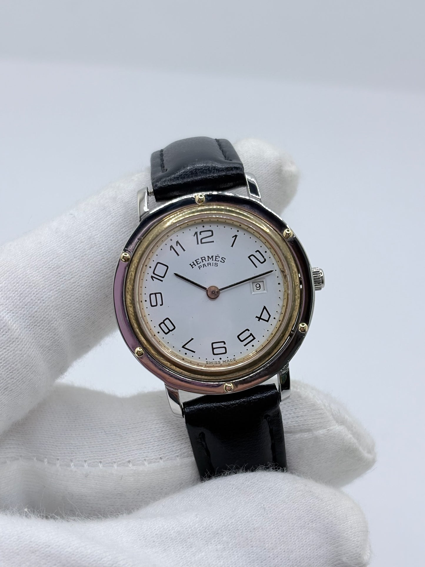 Montre Hermès Clipper pour femme en acier, équipée d’un mouvement à quartz. Son boîtier de 30 mm est associé à une lunette en or jaune, un cadran blanc avec chiffres arabes et un verre saphir. Cette montre Hermès Clipper est montée sur un bracelet en cuir de vache noir avec boucle ardillon en acier. Un modèle élégant et intemporel de la collection Clipper, idéal pour les amateurs de montres de luxe.