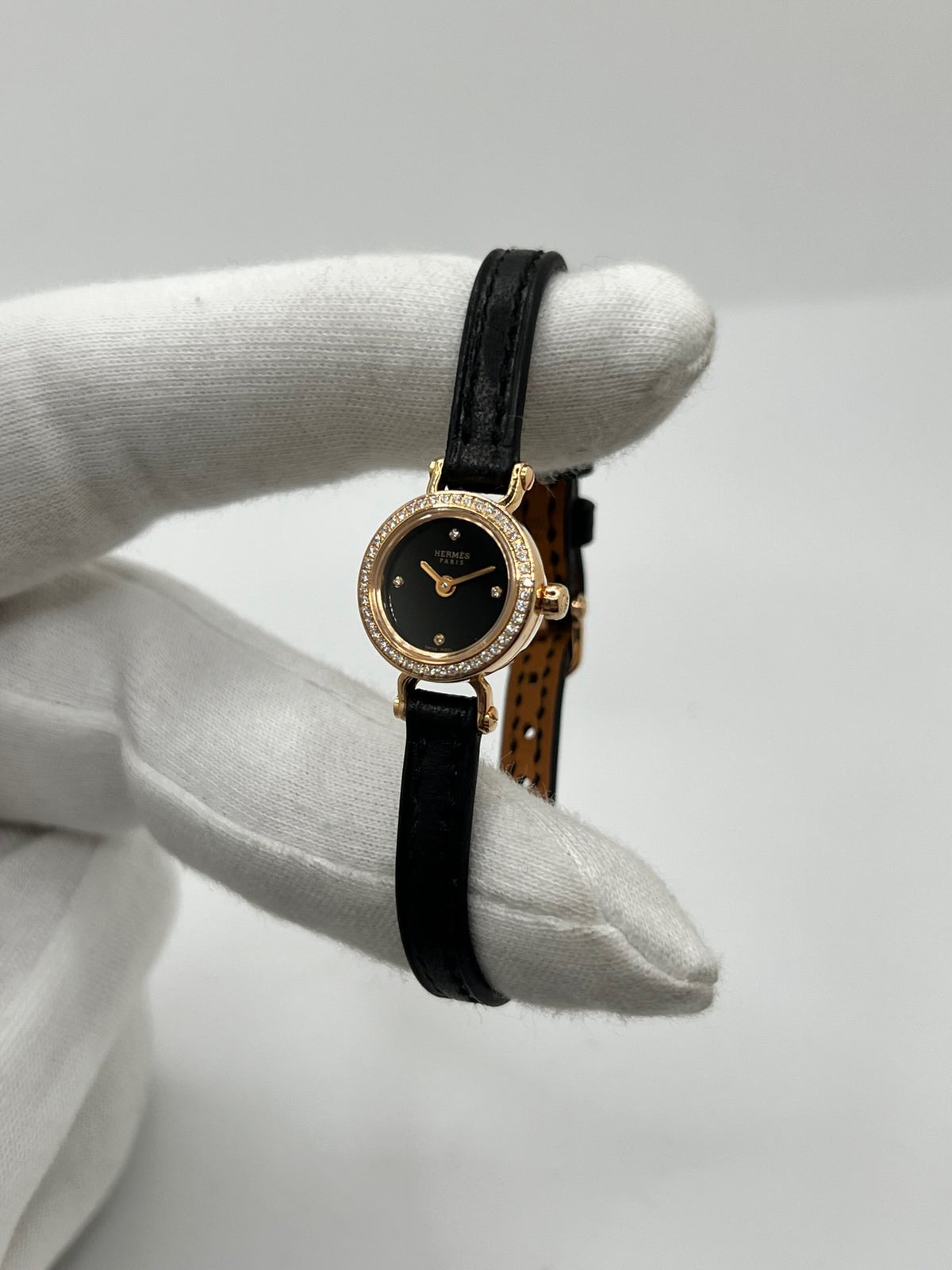 Montre Hermès Faubourg FG4.171 pour femme, dotée d’un élégant boîtier en or rose de 15,5 mm et d’un mouvement quartz. Elle se distingue par son cadran noir sans chiffres, protégé par un verre saphir, et son bracelet en cuir noir avec boucle ardillon en or rose. Cette montre de luxe Hermès associe raffinement, élégance et discrétion. Modèle d’occasion en très bon état, révisé en interne en octobre 2026 et livré avec son coffret d’origine.