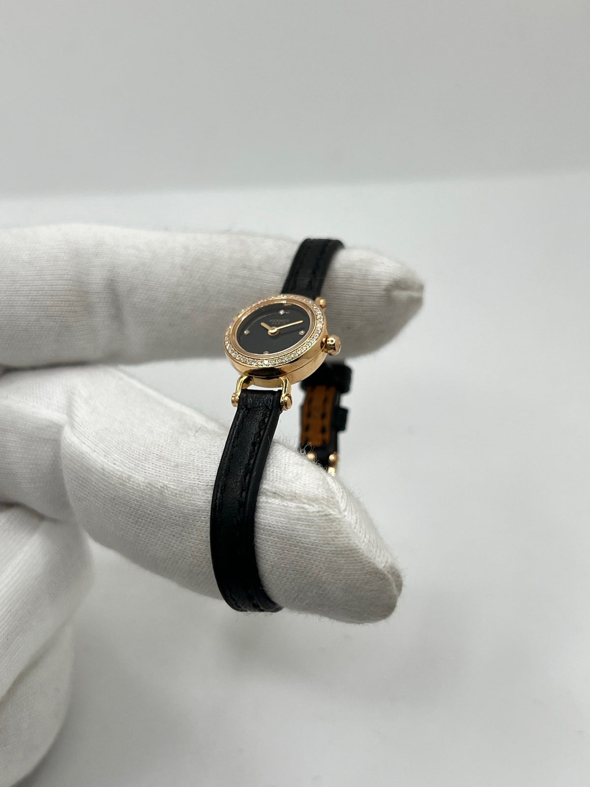 Montre Hermès Faubourg FG4.171 pour femme, dotée d’un élégant boîtier en or rose de 15,5 mm et d’un mouvement quartz. Elle se distingue par son cadran noir sans chiffres, protégé par un verre saphir, et son bracelet en cuir noir avec boucle ardillon en or rose. Cette montre de luxe Hermès associe raffinement, élégance et discrétion. Modèle d’occasion en très bon état, révisé en interne en octobre 2026 et livré avec son coffret d’origine.