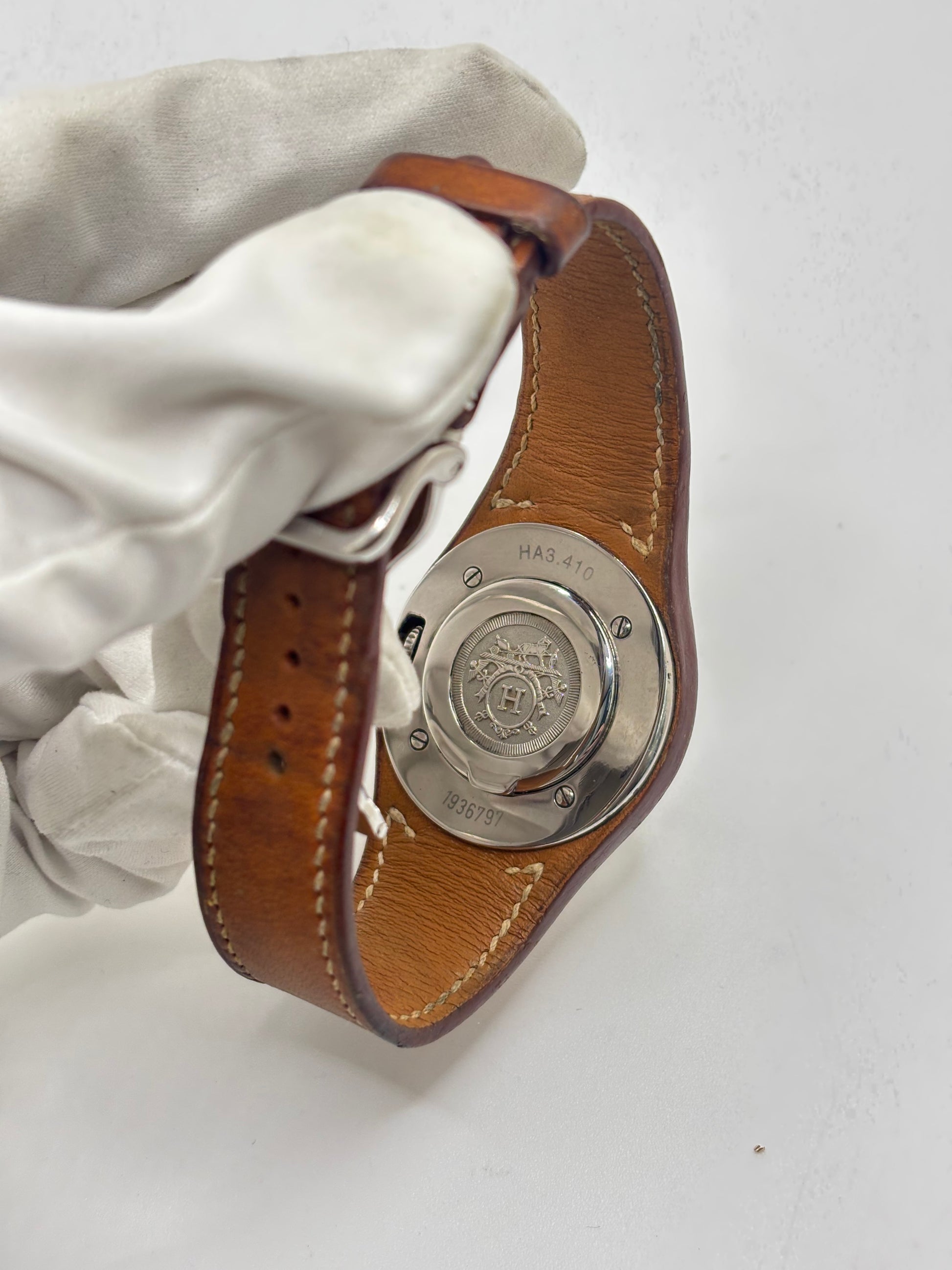 Montre Hermès Harnais HA3.410 en acier avec mouvement quartz, cadran blanc et bracelet en cuir brun. Modèle homme et unisexe au design élégant avec verre saphir et fonction date. Montre d’occasion en très bon état avec légères traces d’usure et micro-rayures discrètes. Format 30 mm idéal pour un style classique et raffiné.
