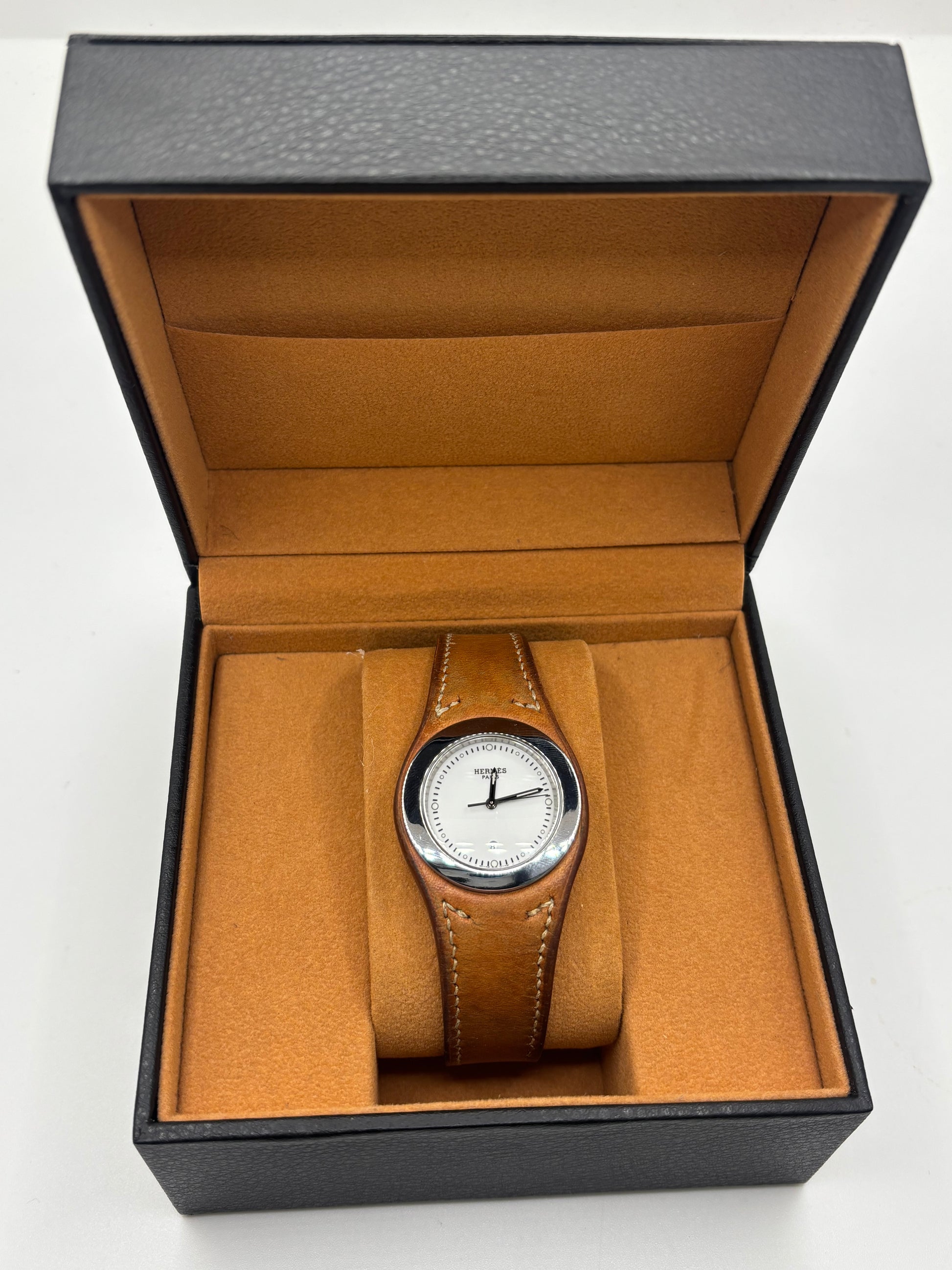 Montre Hermès Harnais HA3.410 en acier avec mouvement quartz, cadran blanc et bracelet en cuir brun. Modèle homme et unisexe au design élégant avec verre saphir et fonction date. Montre d’occasion en très bon état avec légères traces d’usure et micro-rayures discrètes. Format 30 mm idéal pour un style classique et raffiné.