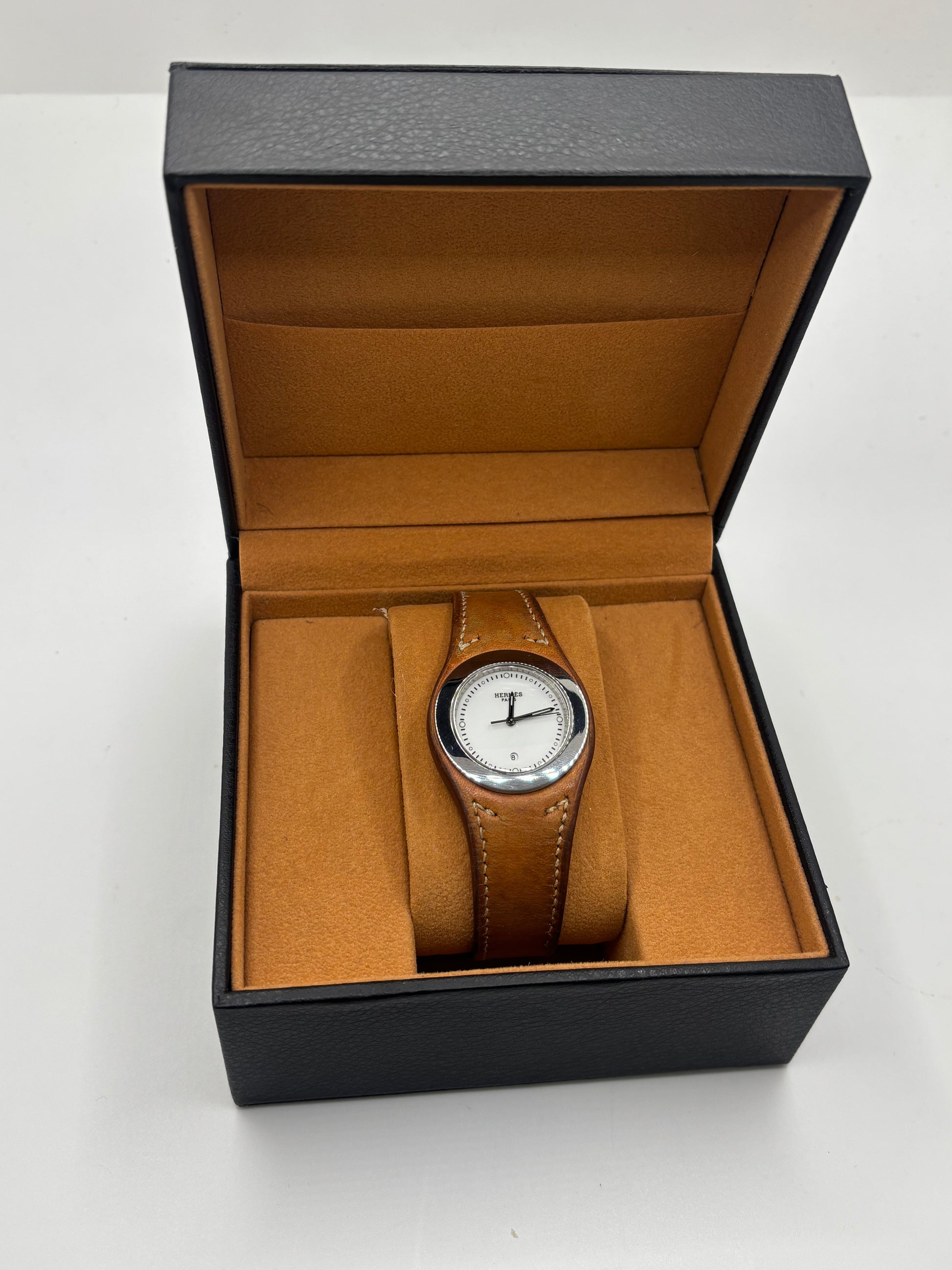 Montre Hermès Harnais HA3.410 en acier avec mouvement quartz, cadran blanc et bracelet en cuir brun. Modèle homme et unisexe au design élégant avec verre saphir et fonction date. Montre d’occasion en très bon état avec légères traces d’usure et micro-rayures discrètes. Format 30 mm idéal pour un style classique et raffiné.