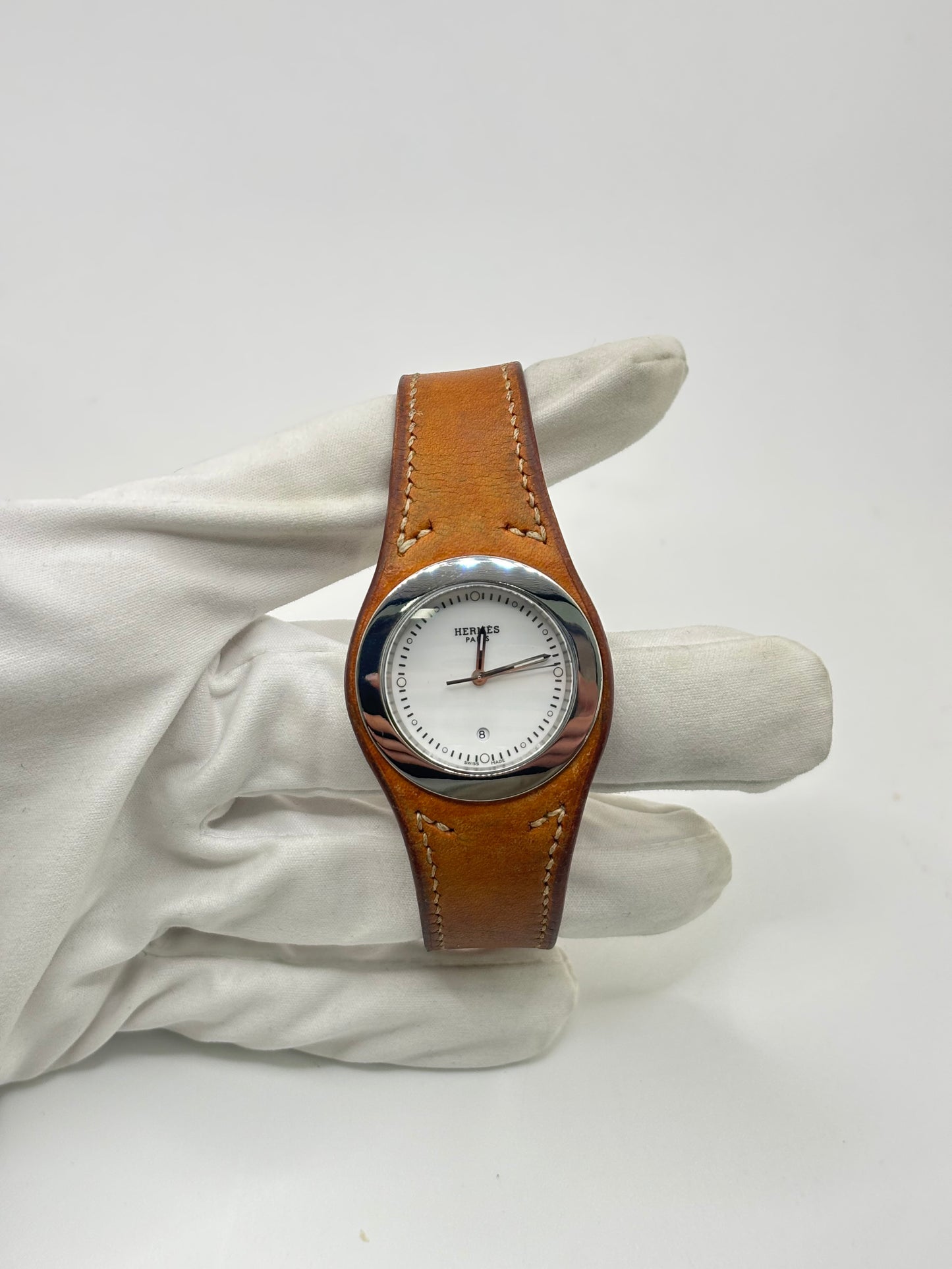 Montre Hermès Harnais HA3.410 en acier avec mouvement quartz, cadran blanc et bracelet en cuir brun. Modèle homme et unisexe au design élégant avec verre saphir et fonction date. Montre d’occasion en très bon état avec légères traces d’usure et micro-rayures discrètes. Format 30 mm idéal pour un style classique et raffiné.
