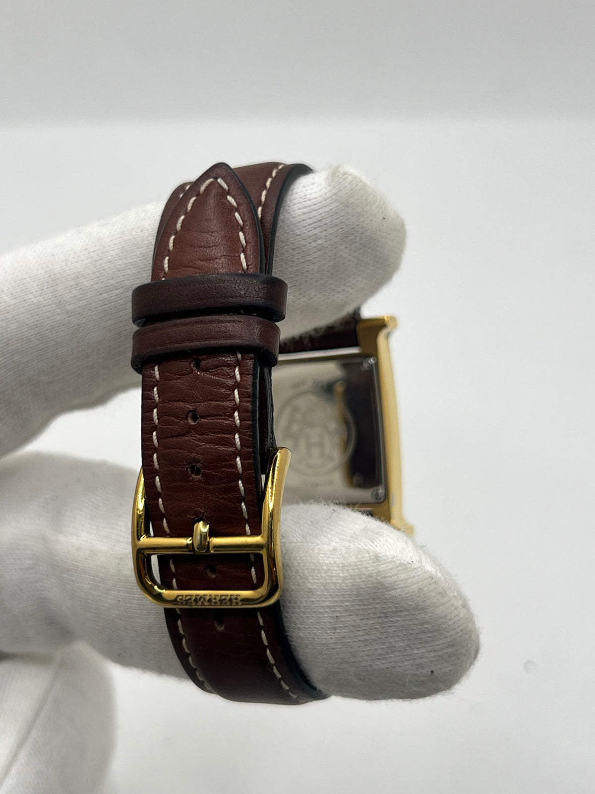 Montre Hermès Heure H HH1.201 pour femme, équipée d’un mouvement quartz et d’un boîtier en acier de 21 mm. Son cadran couleur or est protégé par un verre saphir et accompagné d’un bracelet brun en cuir de vache avec boucle ardillon en acier. Étanche à 3 ATM, cette montre Hermès Heure H se distingue par son célèbre boîtier en forme de H et son design élégant. En très bon état, elle présente de légères traces d’usure.
