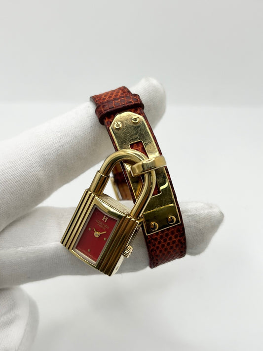 Montre Hermès Kelly KE1.201 pour femme, équipée d’un mouvement à quartz et d’un boîtier plaqué or de 20 × 38 mm. Son cadran rouge apporte une touche de caractère, tandis que le verre saphir protège le cadran. Cette montre Hermès est montée sur un bracelet bordeaux en cuir de lézard avec boucle ardillon en acier. Un modèle élégant et emblématique de la collection Kelly, en bon état, présentant des traces d’usure visibles.