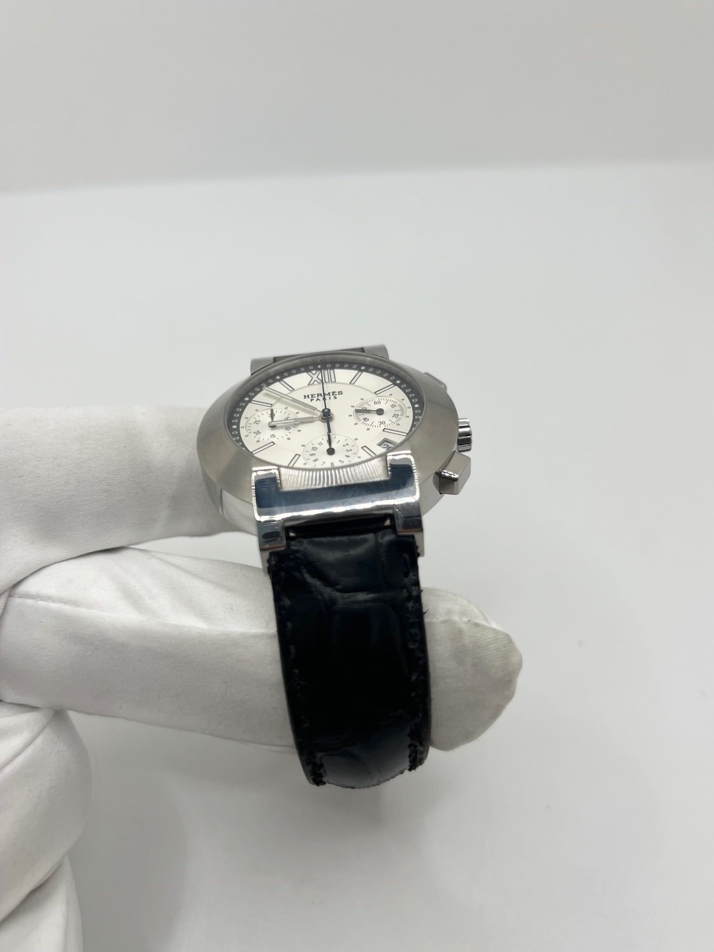 Montre Hermès Nomade Chronograph en acier avec boîtier de 39 mm et cadran blanc à index bâtons. Ce chronographe à mouvement quartz est équipé d’un verre saphir, d’un affichage de la date et d’un bracelet en cuir de crocodile gris avec boucle déployante en acier. Son design élégant et sportif reflète le savoir-faire horloger de la maison Hermès. Modèle unisexe d’occasion en très bon état, alliant confort, précision et raffinement au quotidien.
