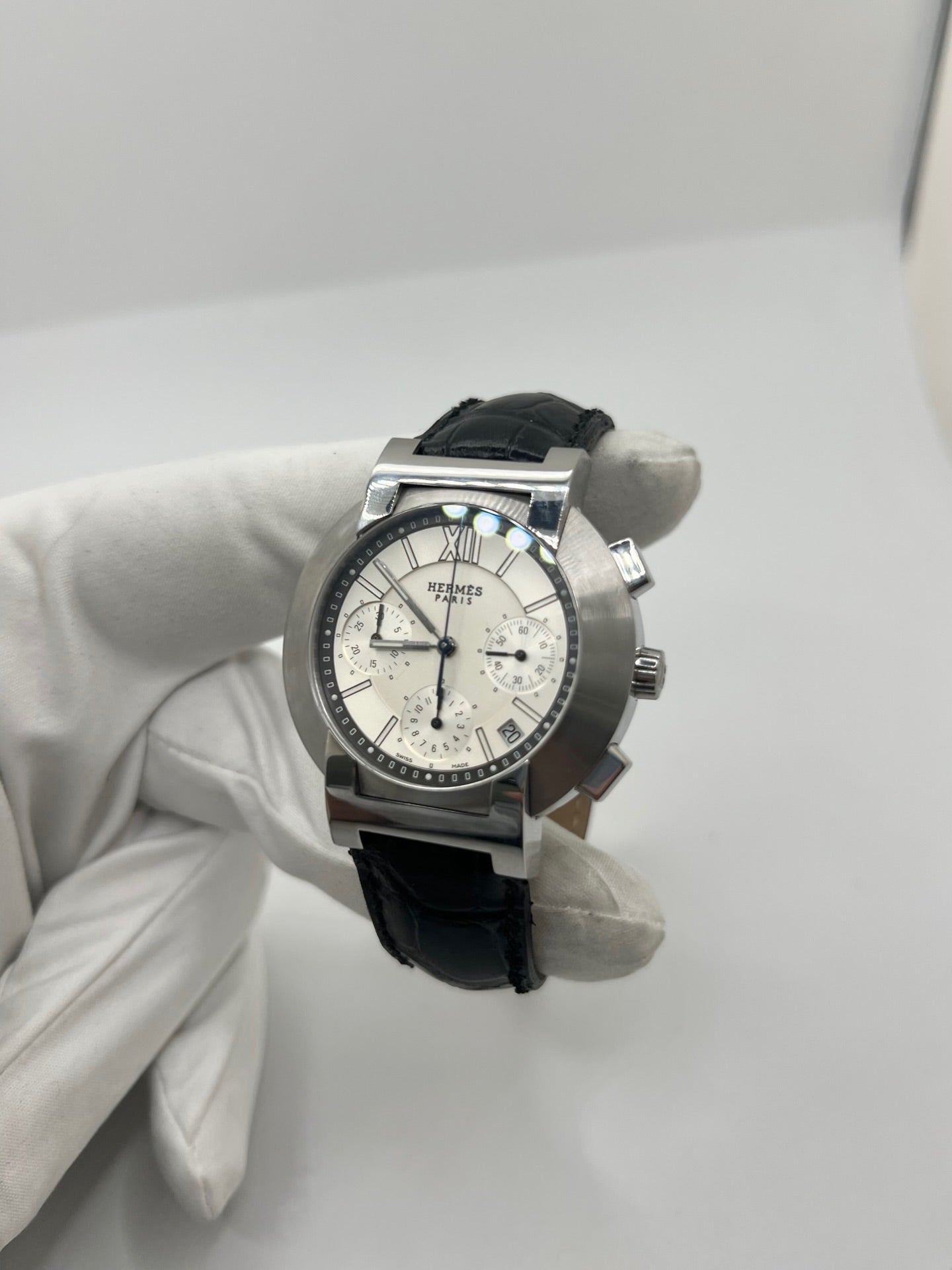 Montre Hermès Nomade Chronograph en acier avec boîtier de 39 mm et cadran blanc à index bâtons. Ce chronographe à mouvement quartz est équipé d’un verre saphir, d’un affichage de la date et d’un bracelet en cuir de crocodile gris avec boucle déployante en acier. Son design élégant et sportif reflète le savoir-faire horloger de la maison Hermès. Modèle unisexe d’occasion en très bon état, alliant confort, précision et raffinement au quotidien.
