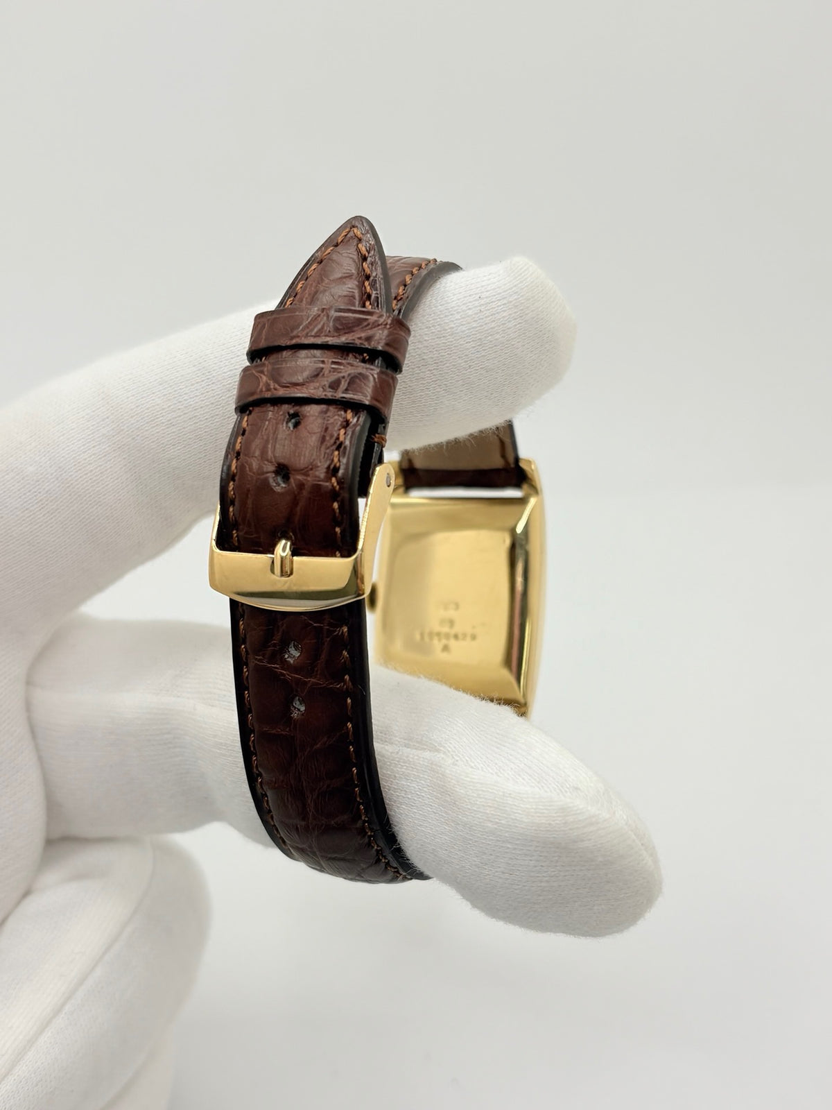 Montre Jaeger-LeCoultre Classic 9012 vintage à remontage manuel, datant approximativement de 1960. Son boîtier rectangulaire en or jaune de 37 × 23 mm est équipé d’un verre Plexiglas et d’un élégant cadran or à index bâtons. Cette montre Jaeger-LeCoultre est montée sur un bracelet brun en cuir de crocodile avec boucle ardillon en acier. En très bon état, elle présente de légères traces d’usure et est proposée avec son coffret d’origine.