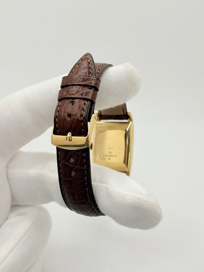 Montre Jaeger-LeCoultre Classic 9012 vintage à remontage manuel, datant approximativement de 1960. Son boîtier rectangulaire en or jaune de 37 × 23 mm est équipé d’un verre Plexiglas et d’un élégant cadran or à index bâtons. Cette montre Jaeger-LeCoultre est montée sur un bracelet brun en cuir de crocodile avec boucle ardillon en acier. En très bon état, elle présente de légères traces d’usure et est proposée avec son coffret d’origine.