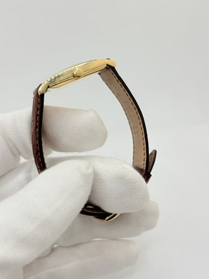 Montre Jaeger-LeCoultre Classic 9012 vintage à remontage manuel, datant approximativement de 1960. Son boîtier rectangulaire en or jaune de 37 × 23 mm est équipé d’un verre Plexiglas et d’un élégant cadran or à index bâtons. Cette montre Jaeger-LeCoultre est montée sur un bracelet brun en cuir de crocodile avec boucle ardillon en acier. En très bon état, elle présente de légères traces d’usure et est proposée avec son coffret d’origine.