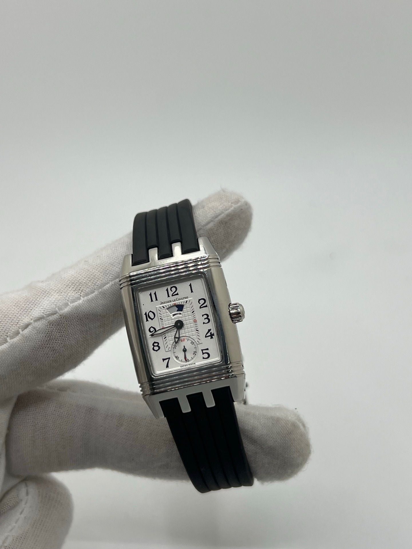 Montre Reverso Duetto référence 296.8.74 en acier, format rectangulaire, équipée d’un mouvement à remontage manuel. Modèle pour femme avec cadran blanc à chiffres arabes et verre saphir. Brace­let en caoutchouc noir avec boucle double plis. Pièce d’occasion en très bon état, présentant de légères traces d’usure discrètes.
