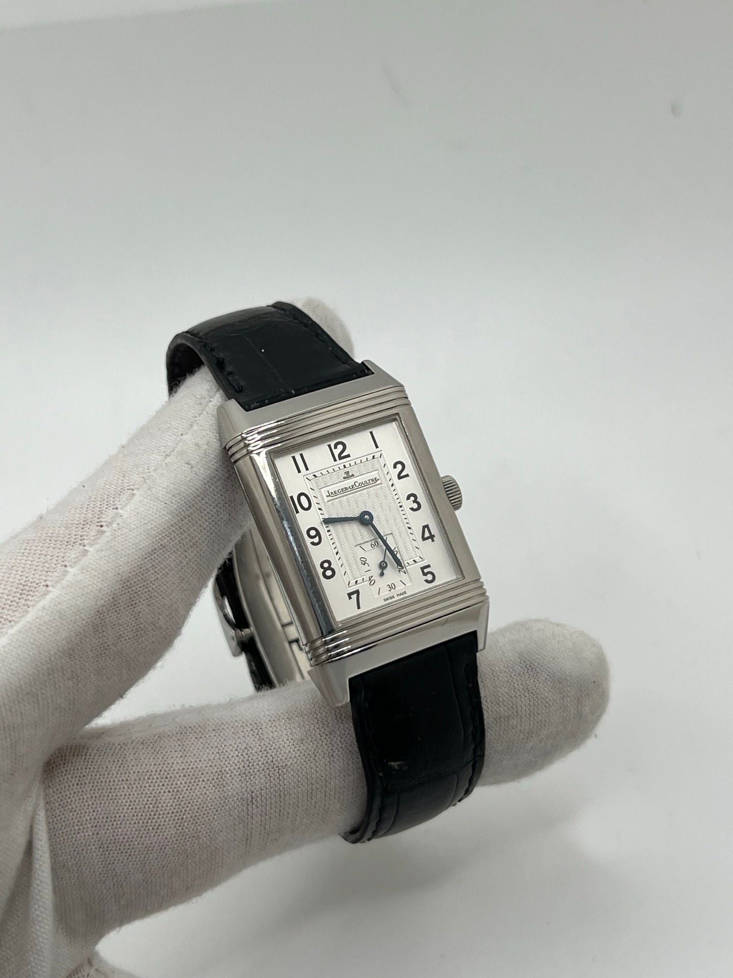 Découvrez la Jaeger-LeCoultre Reverso Grande Taille pour homme/unisexe, modèle 2008 en acier avec bracelet cuir brun. Montre de luxe à remontage manuel, calibre 822, 45 h de réserve de marche, petite seconde et cadran argent. État très bon, avec coffret et papiers d’origine.