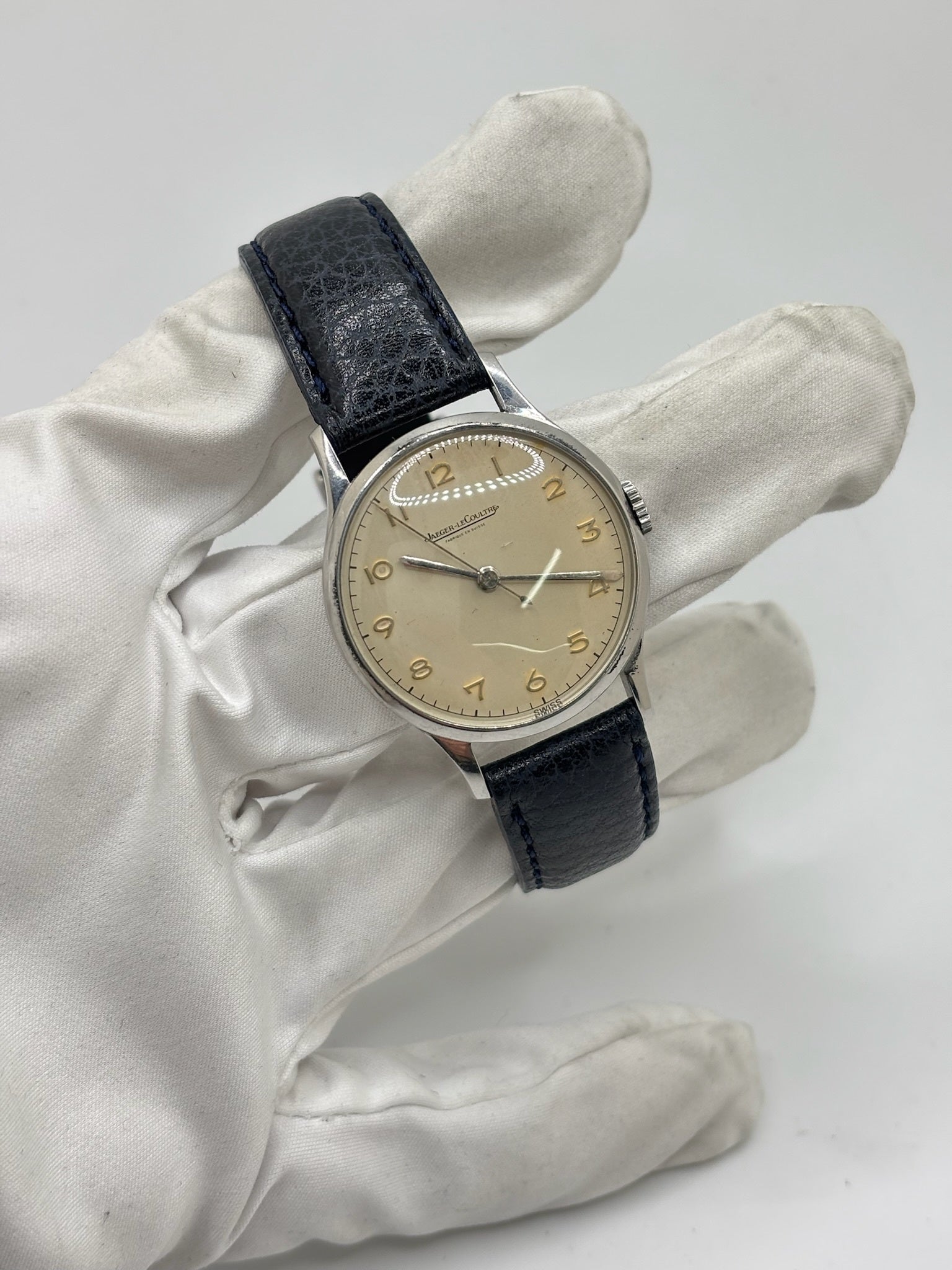 Montre Jaeger-LeCoultre vintage en acier datant des années 1950, équipée du calibre P478 à remontage manuel. Son cadran argent à chiffres arabes est protégé par un verre plexiglas et associé à un bracelet en cuir noir. Avec son boîtier de 31,5 mm et son design sobre et élégant, cette montre mécanique de collection illustre le savoir-faire horloger suisse de l'époque. Pièce ancienne recherchée par les amateurs de montres vintage et de garde-temps de caractère.