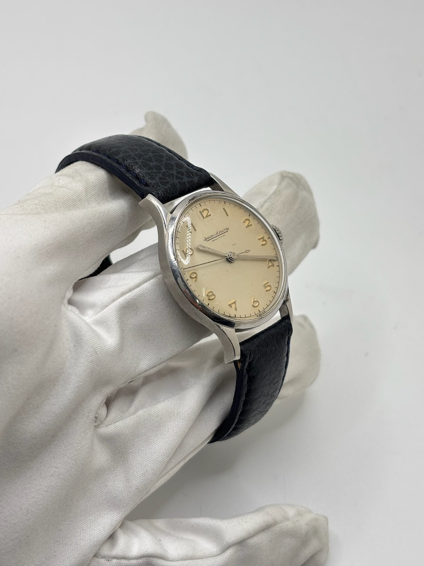 Montre Jaeger-LeCoultre vintage en acier datant des années 1950, équipée du calibre P478 à remontage manuel. Son cadran argent à chiffres arabes est protégé par un verre plexiglas et associé à un bracelet en cuir noir. Avec son boîtier de 31,5 mm et son design sobre et élégant, cette montre mécanique de collection illustre le savoir-faire horloger suisse de l'époque. Pièce ancienne recherchée par les amateurs de montres vintage et de garde-temps de caractère.