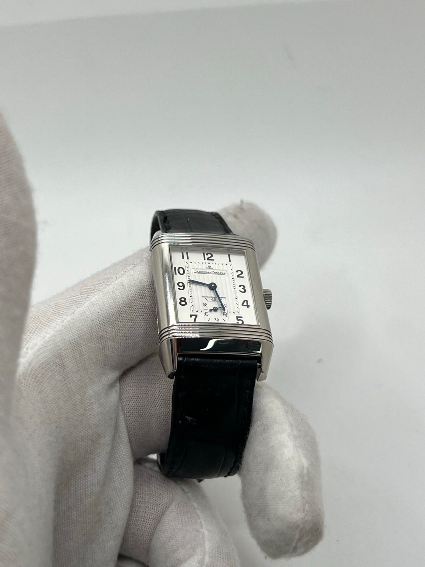 Découvrez la Jaeger-LeCoultre Reverso Grande Taille pour homme/unisexe, modèle 2008 en acier avec bracelet cuir brun. Montre de luxe à remontage manuel, calibre 822, 45 h de réserve de marche, petite seconde et cadran argent. État très bon, avec coffret et papiers d’origine.